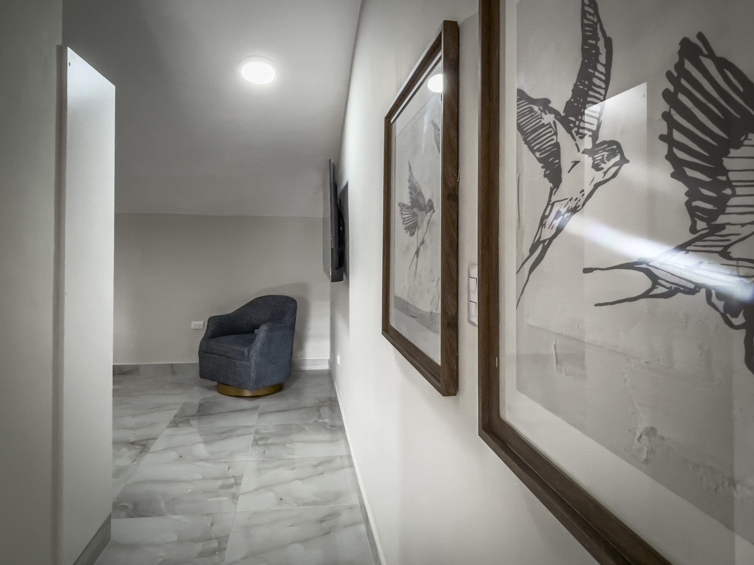 buyDRproperty Stylish 1-bedroom condo hallway with artwork and blue armchair Sosua Real Estate
