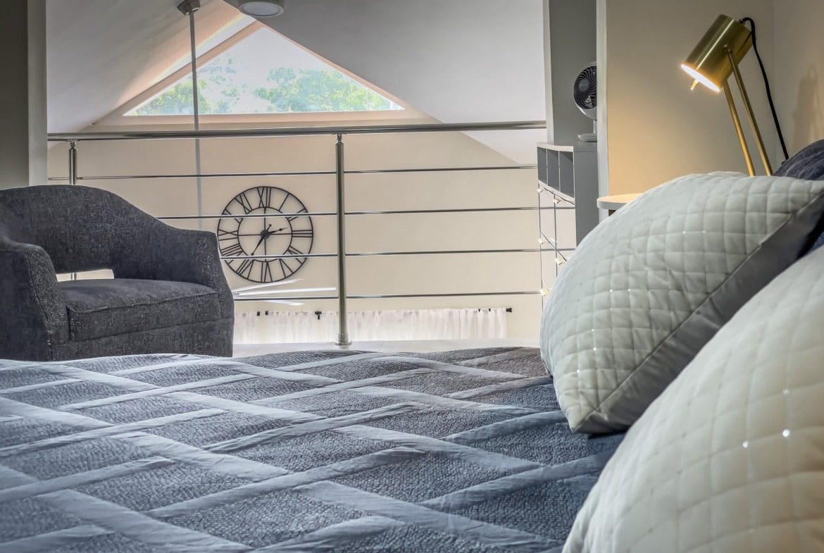buyDRproperty Cozy 1-Bedroom Condo loft bedroom with bed, pillows, and accent chair. Sosua Real Estate