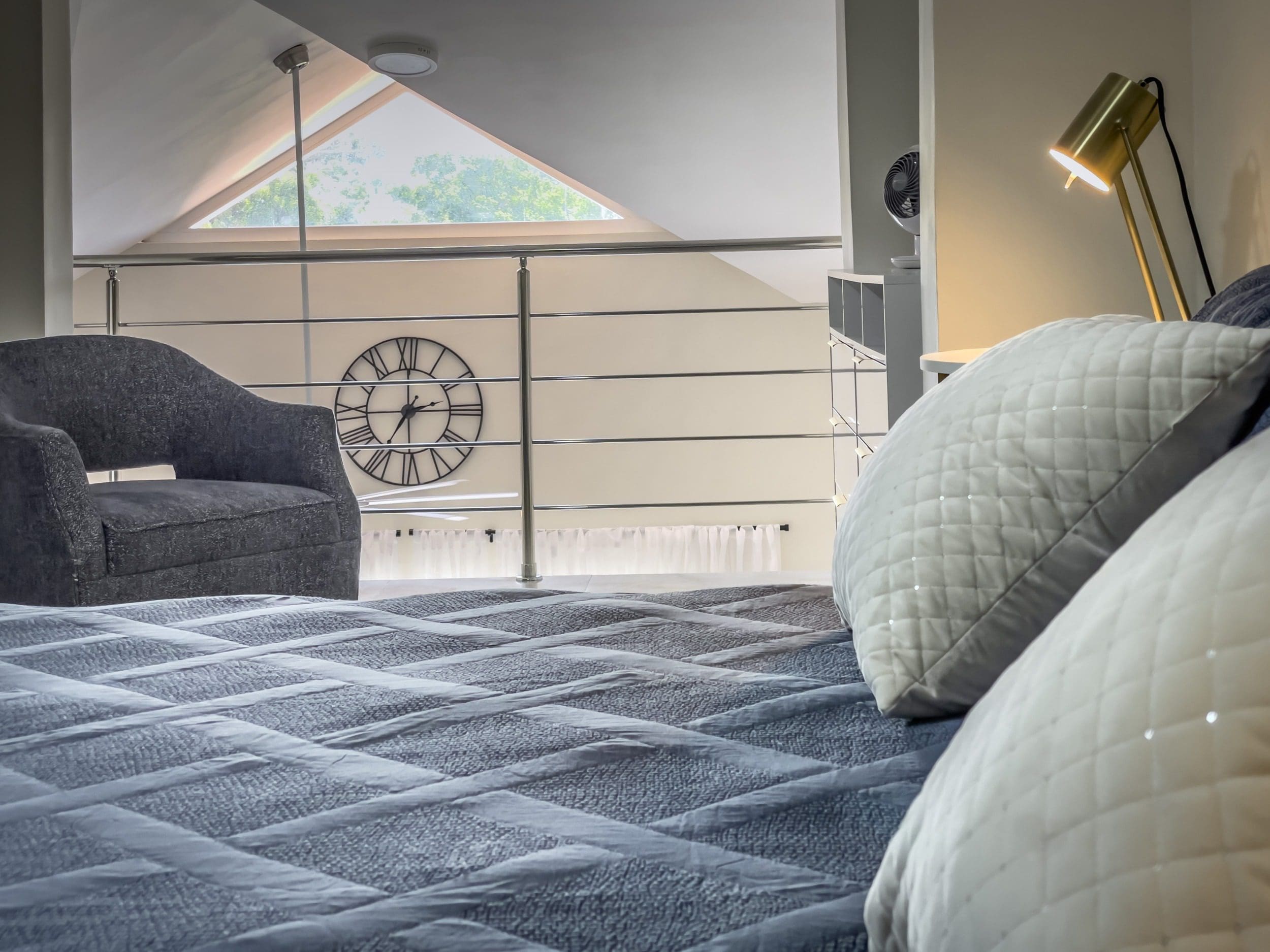 buyDRproperty Cozy 1-Bedroom Condo loft bedroom with bed, pillows, and accent chair. Sosua Real Estate