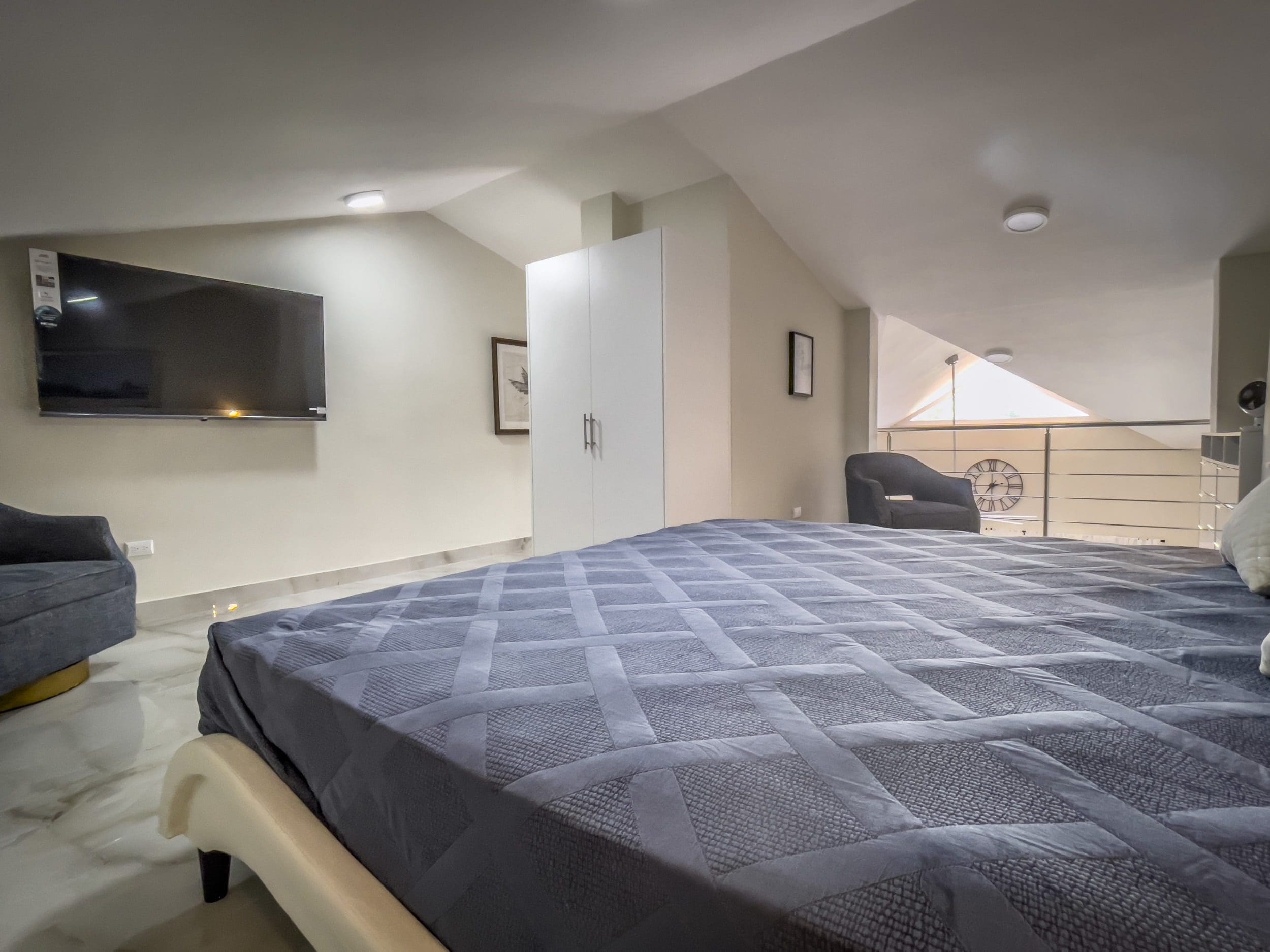 buyDRproperty Modern loft bedroom in a 1-Bedroom Condo with a large bed and TV. Sosua Real Estate