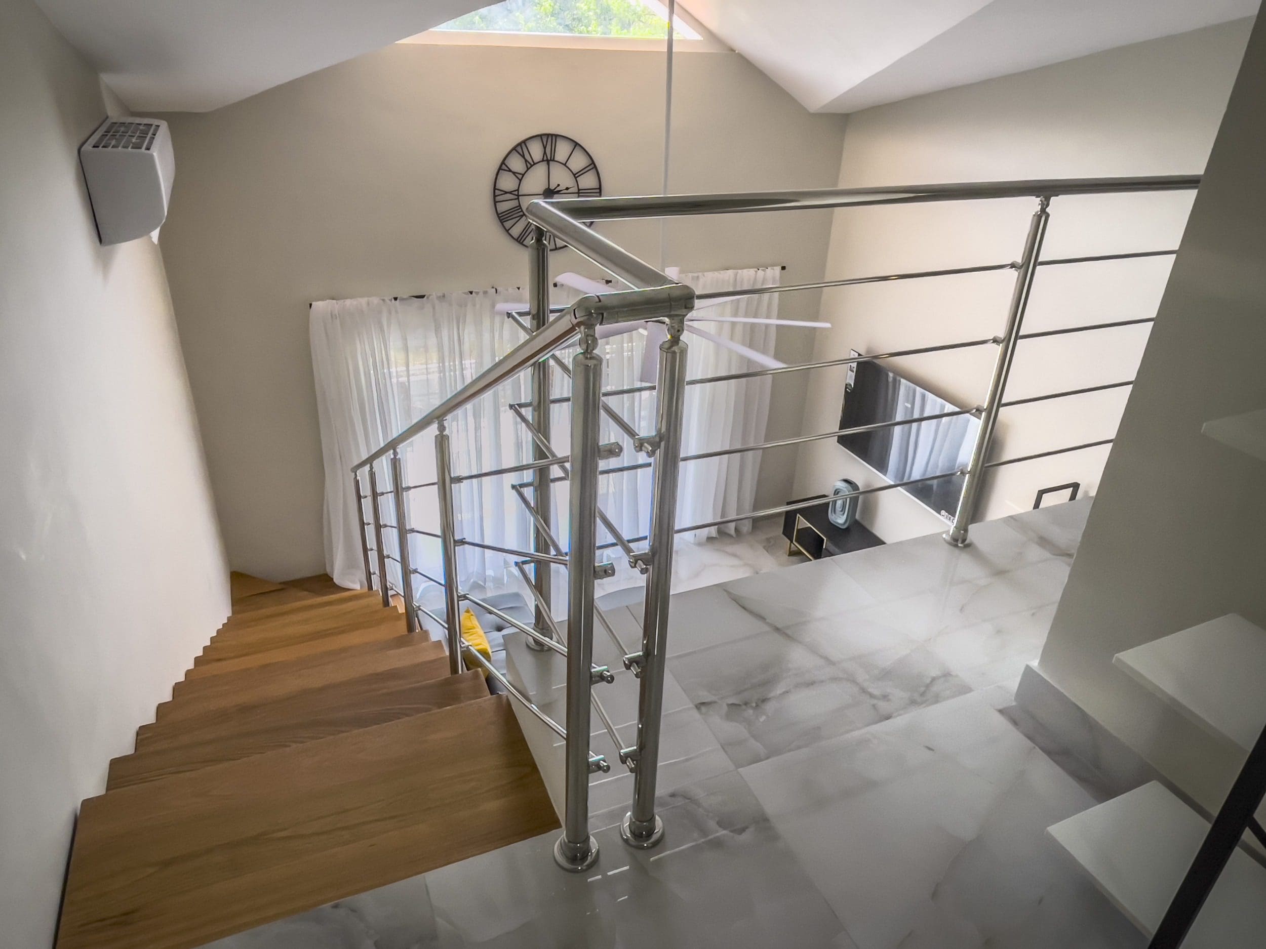 buyDRproperty Staircase in a modern 1-bedroom condo with stainless steel railing and wood steps. Sosua Real Estate
