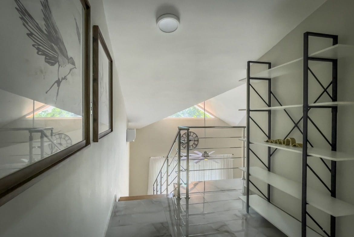 buyDRproperty Stylish 1-bedroom condo with modern staircase and decorative wall art. Sosua Real Estate
