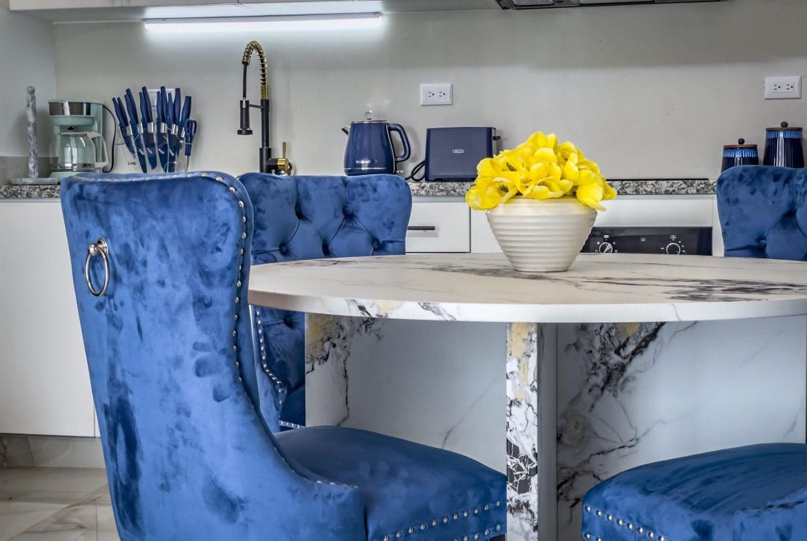 buyDRproperty Modern 1-Bedroom Condo: Stylish blue velvet dining chairs in a modern kitchen. Sosua Real Estate