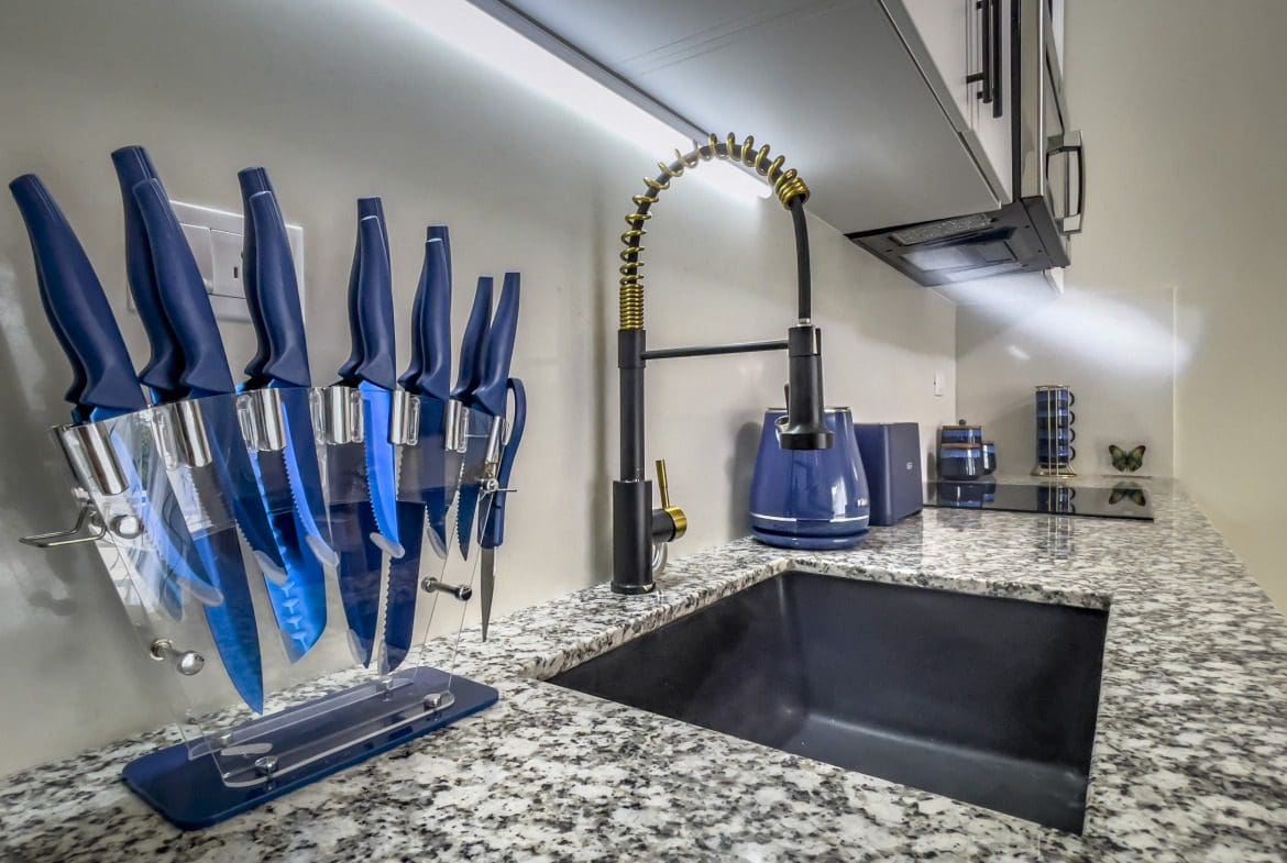 buyDRproperty Modern kitchen in a 1-bedroom condo with black sink and blue knives. Sosua Real Estate
