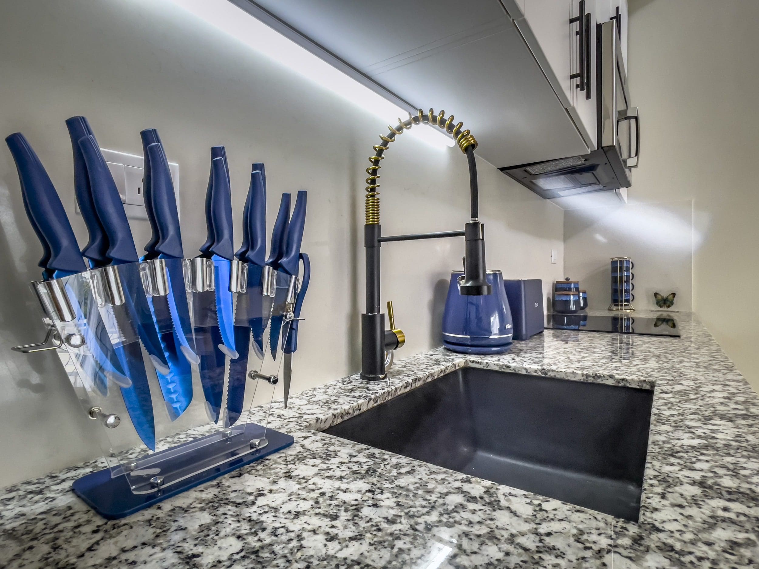 buyDRproperty Modern kitchen in a 1-bedroom condo with black sink and blue knives. Sosua Real Estate