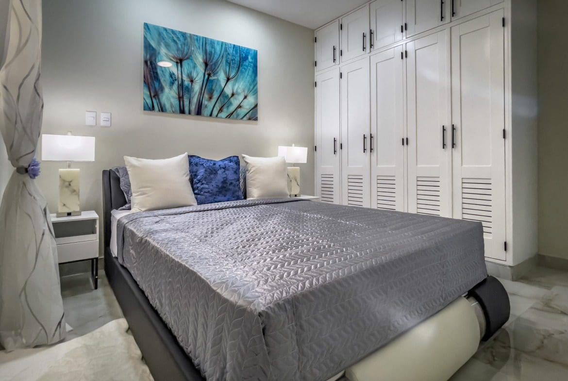 buyDRproperty Modern 1-bedroom condo bedroom with gray bedding and white built-in closet Sosua Real Estate