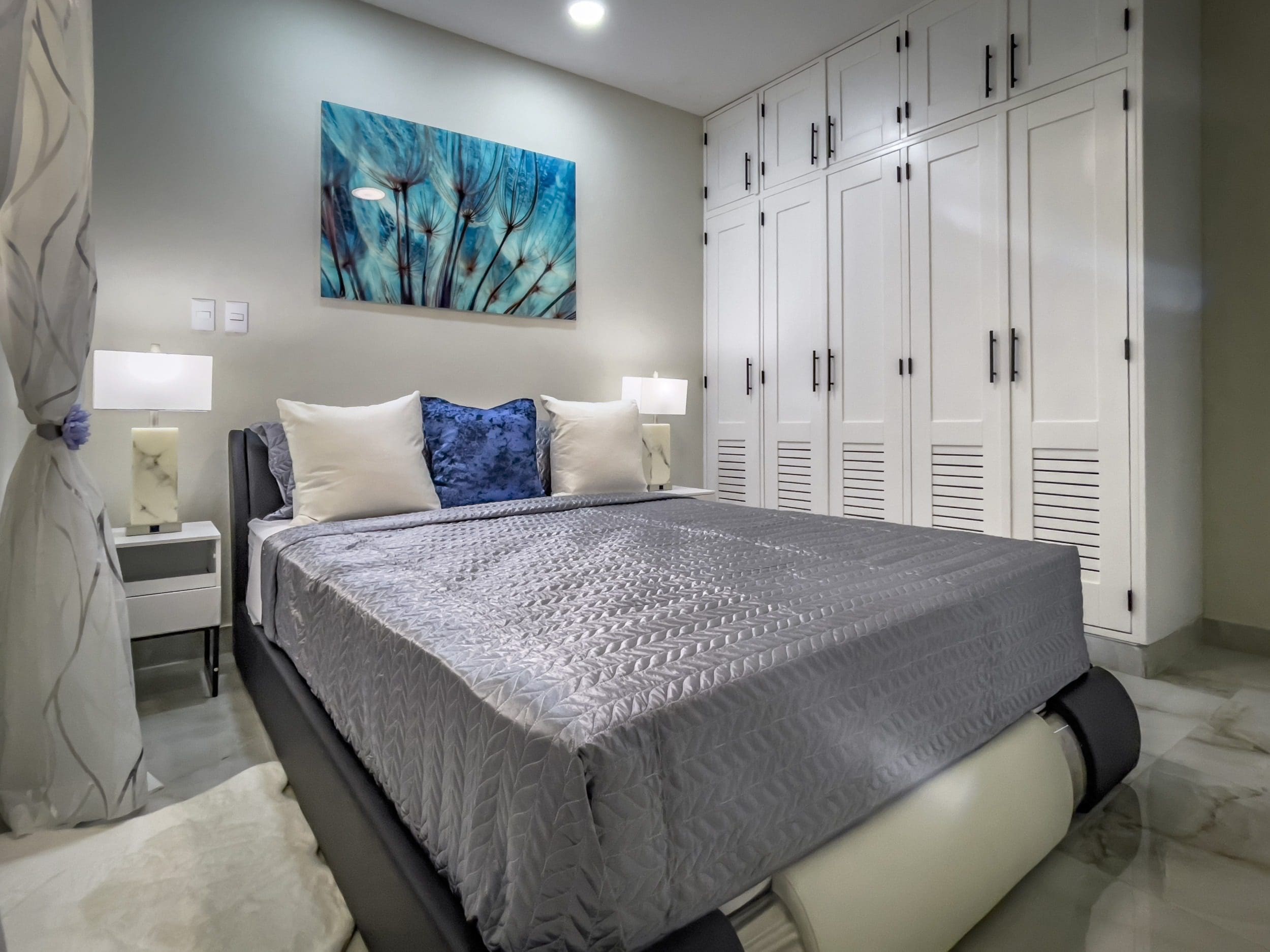 buyDRproperty Modern 1-bedroom condo bedroom with gray bedding and white built-in closet Sosua Real Estate