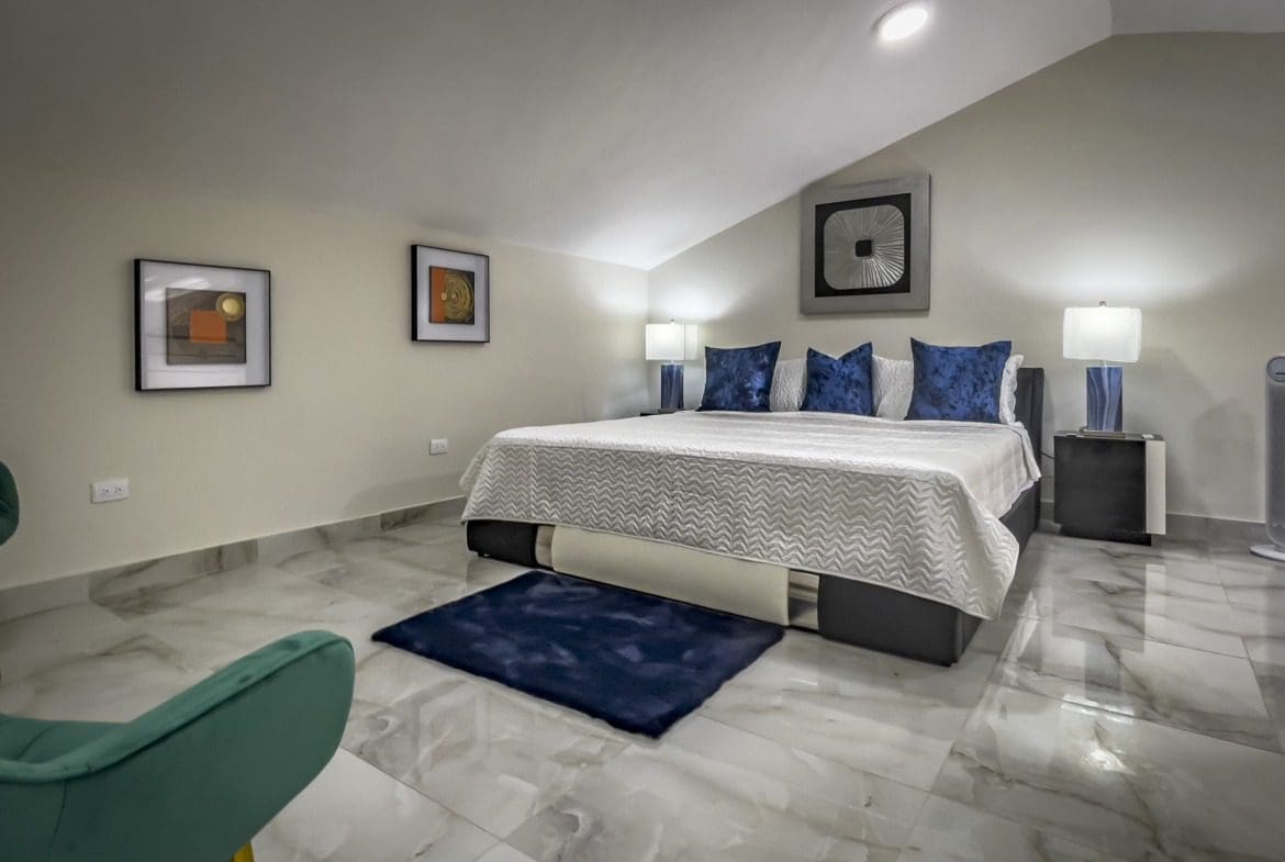 buyDRproperty Modern 1-bedroom condo loft bedroom with blue accents and artwork. Sosua Real Estate