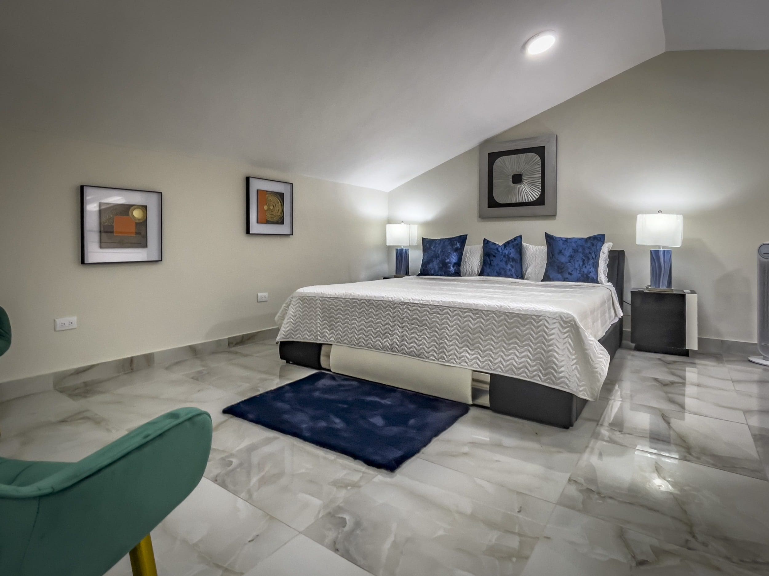 buyDRproperty Modern 1-bedroom condo loft bedroom with blue accents and artwork. Sosua Real Estate