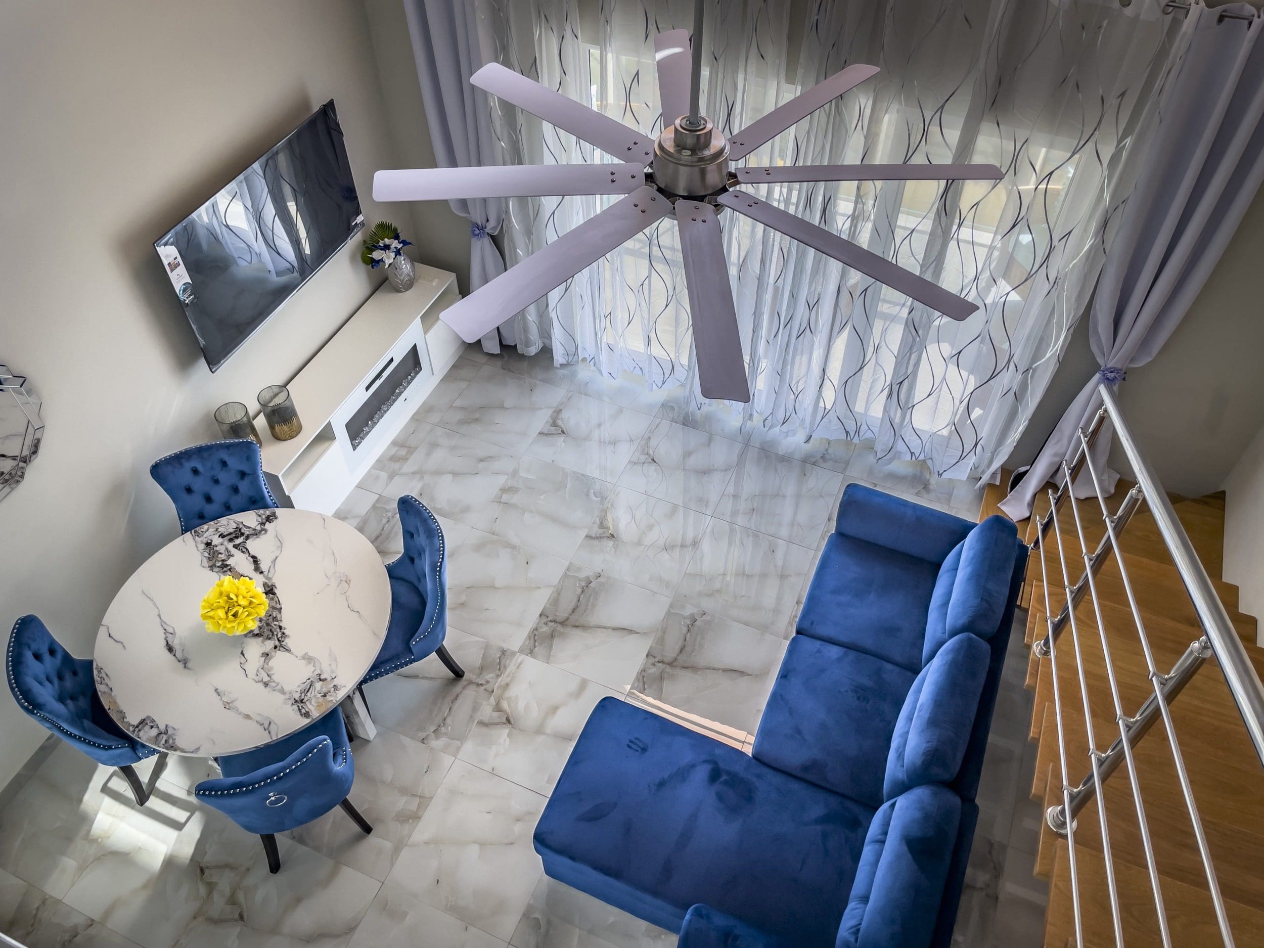 buyDRproperty Modern 1-Bedroom Condo living room with blue velvet sofa, dining table, and ceiling fan. Sosua Real Estate