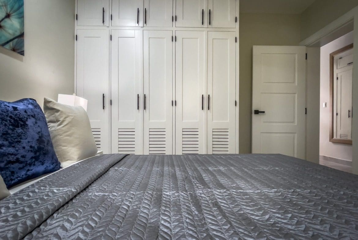 buyDRproperty Modern 1-Bedroom Condo bedroom with white wardrobe and grey bedspread. Sosua Real Estate