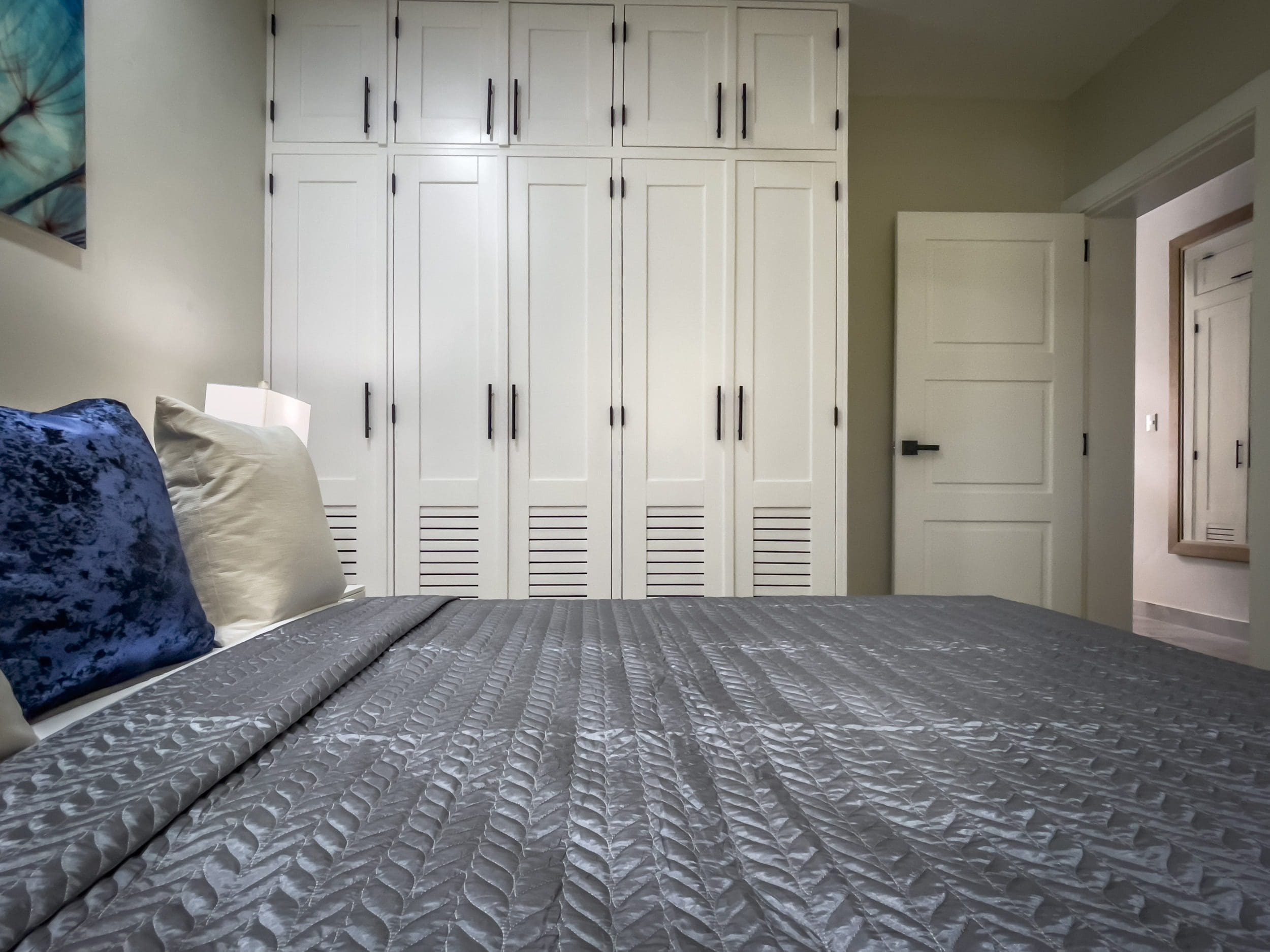 buyDRproperty Modern 1-Bedroom Condo bedroom with white wardrobe and grey bedspread. Sosua Real Estate