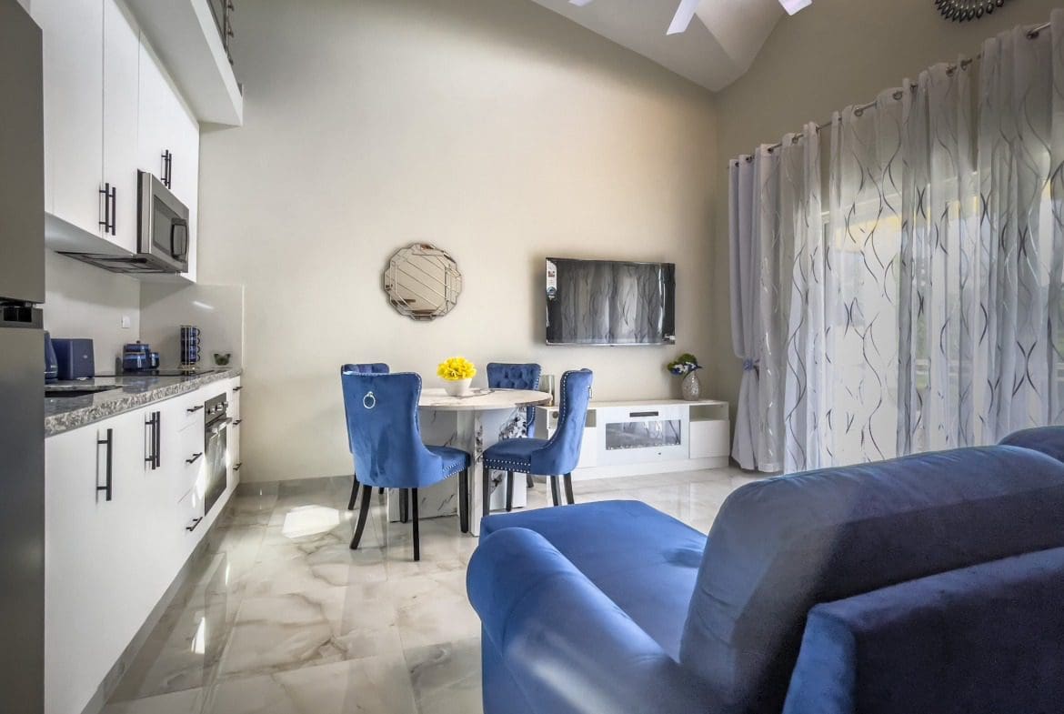 buyDRproperty Modern 1-Bedroom Condo interior with blue sofa, dining area, and kitchen. Sosua Real Estate