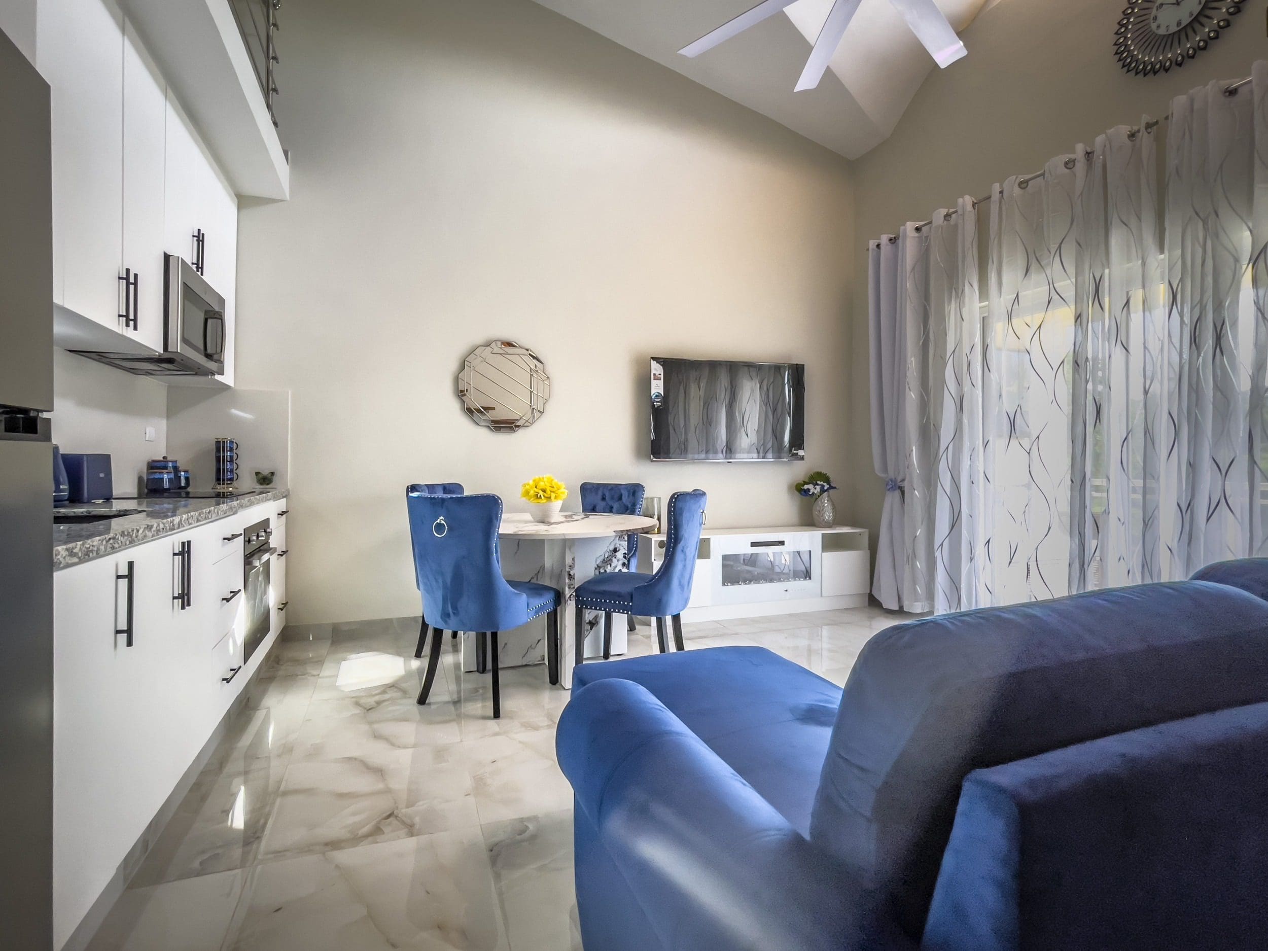 buyDRproperty Modern 1-Bedroom Condo interior with blue sofa, dining area, and kitchen. Sosua Real Estate