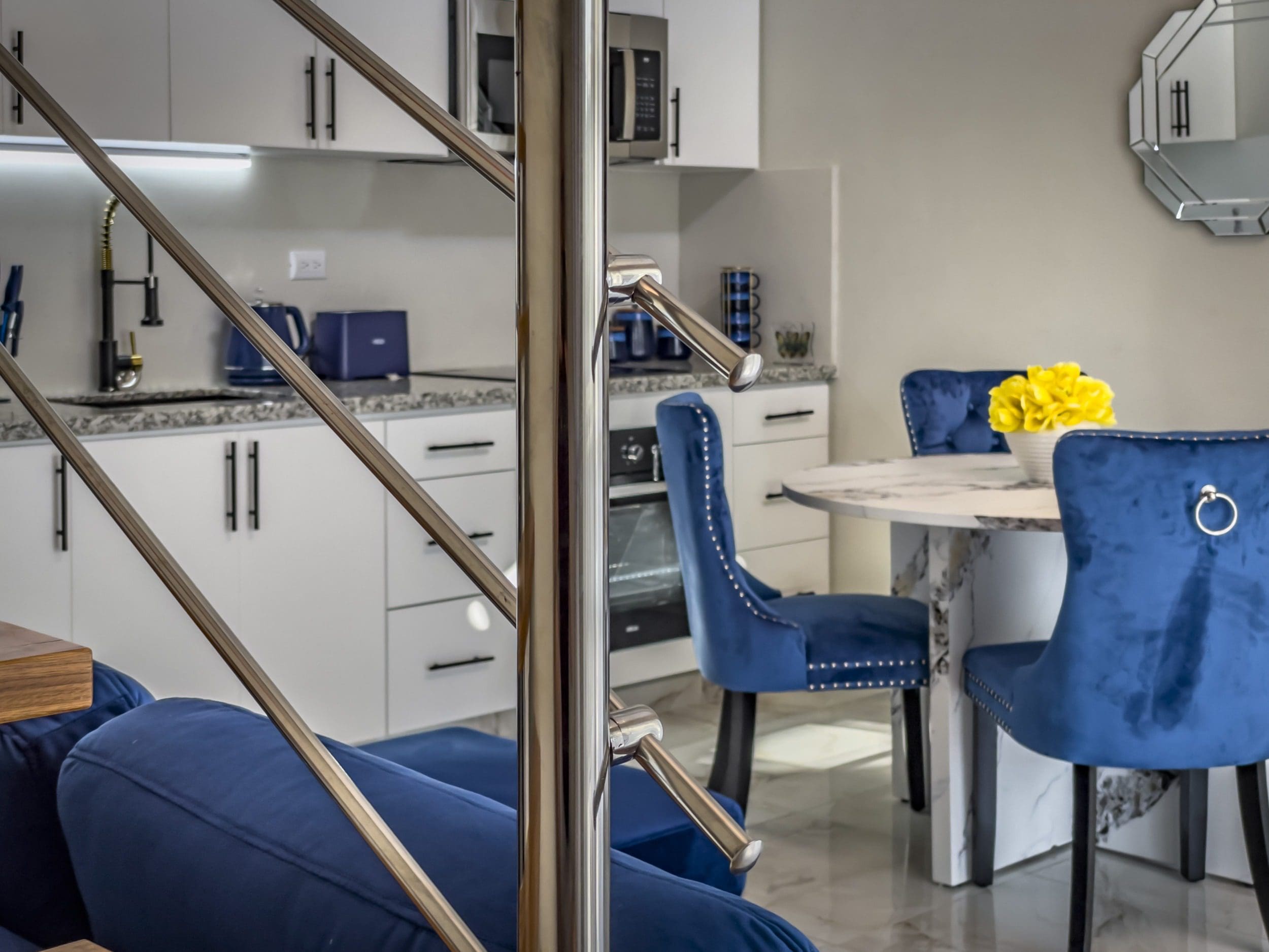 buyDRproperty Modern 1-Bedroom Condo interior with stainless steel staircase and blue velvet dining chairs. Sosua Real Estate