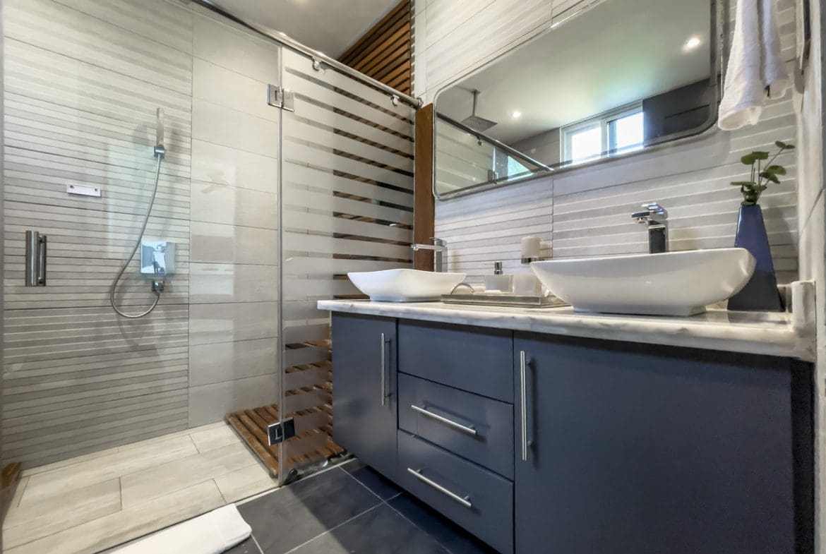 buyDRproperty Modern bathroom in a Sosúa Ocean Village villa for sale, featuring a glass shower and vessel sinks. Sosua Real Estate