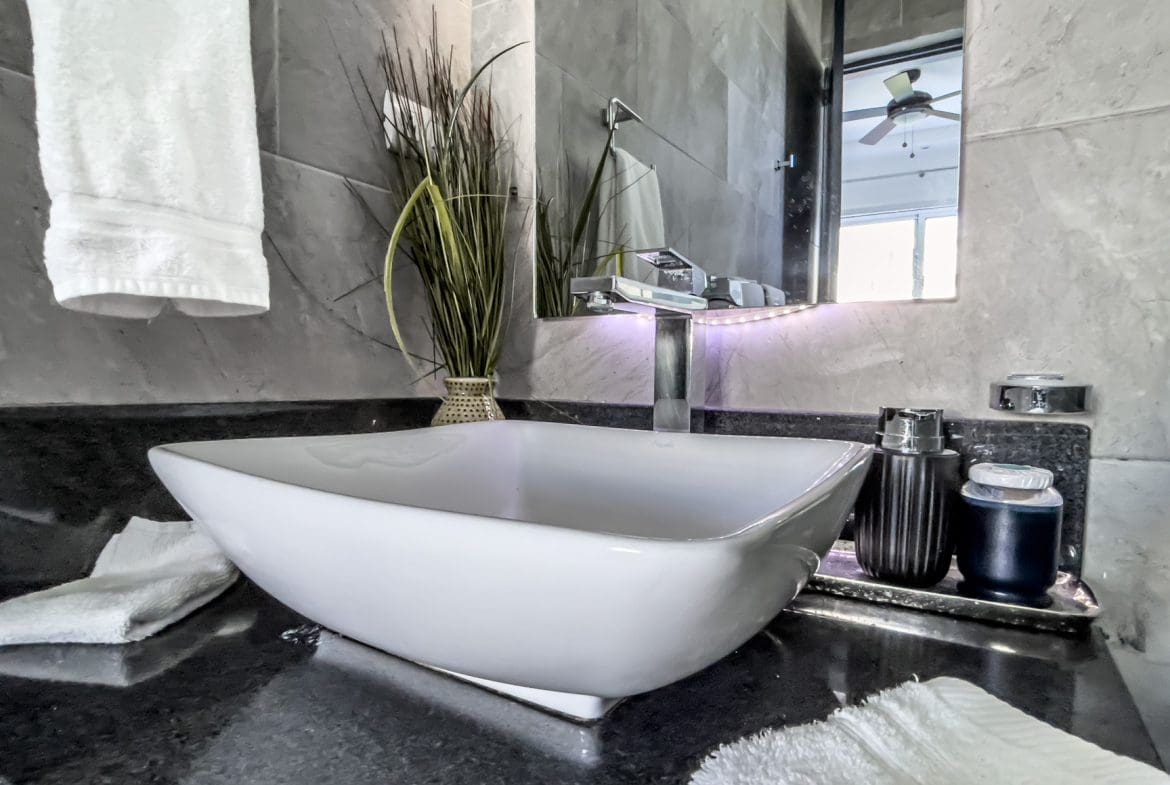 buyDRproperty Modern bathroom with a white vessel sink and black countertop. Ocean view villa in Sosúa. Sosua Real Estate