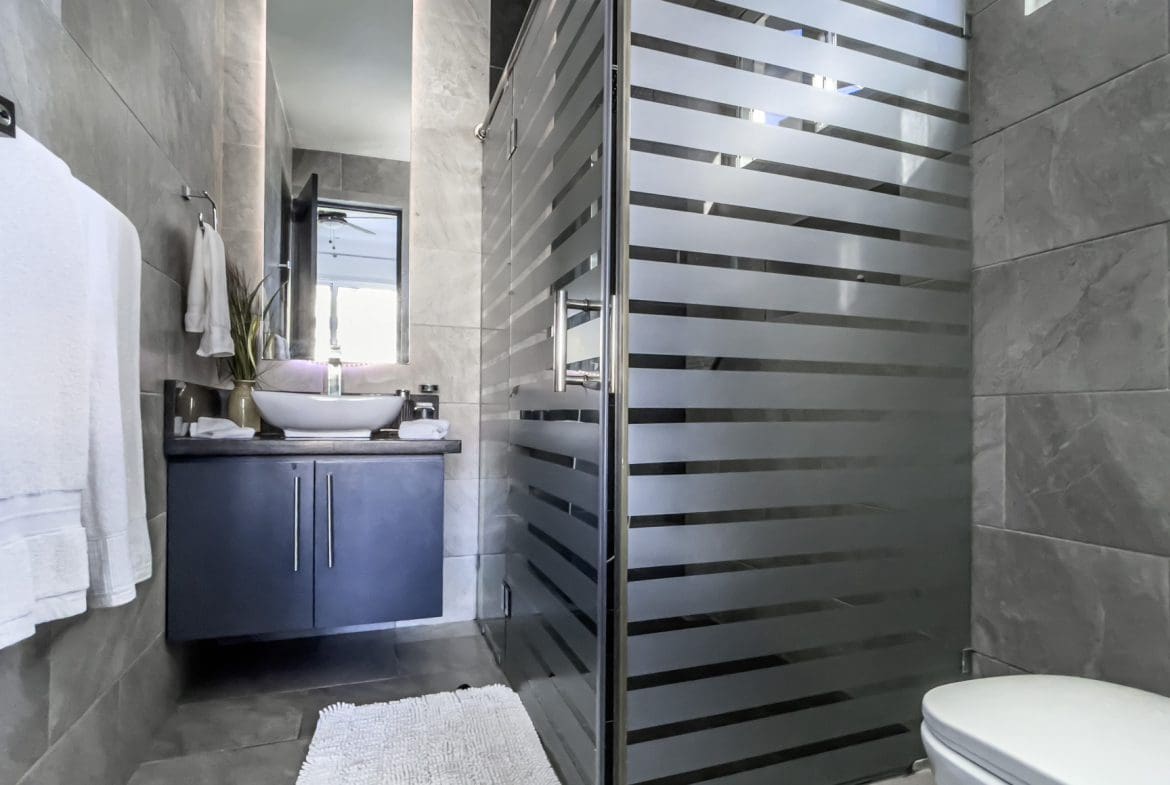 buyDRproperty Modern bathroom with frosted glass shower in a Sosúa Ocean Village villa for sale. Sosua Real Estate