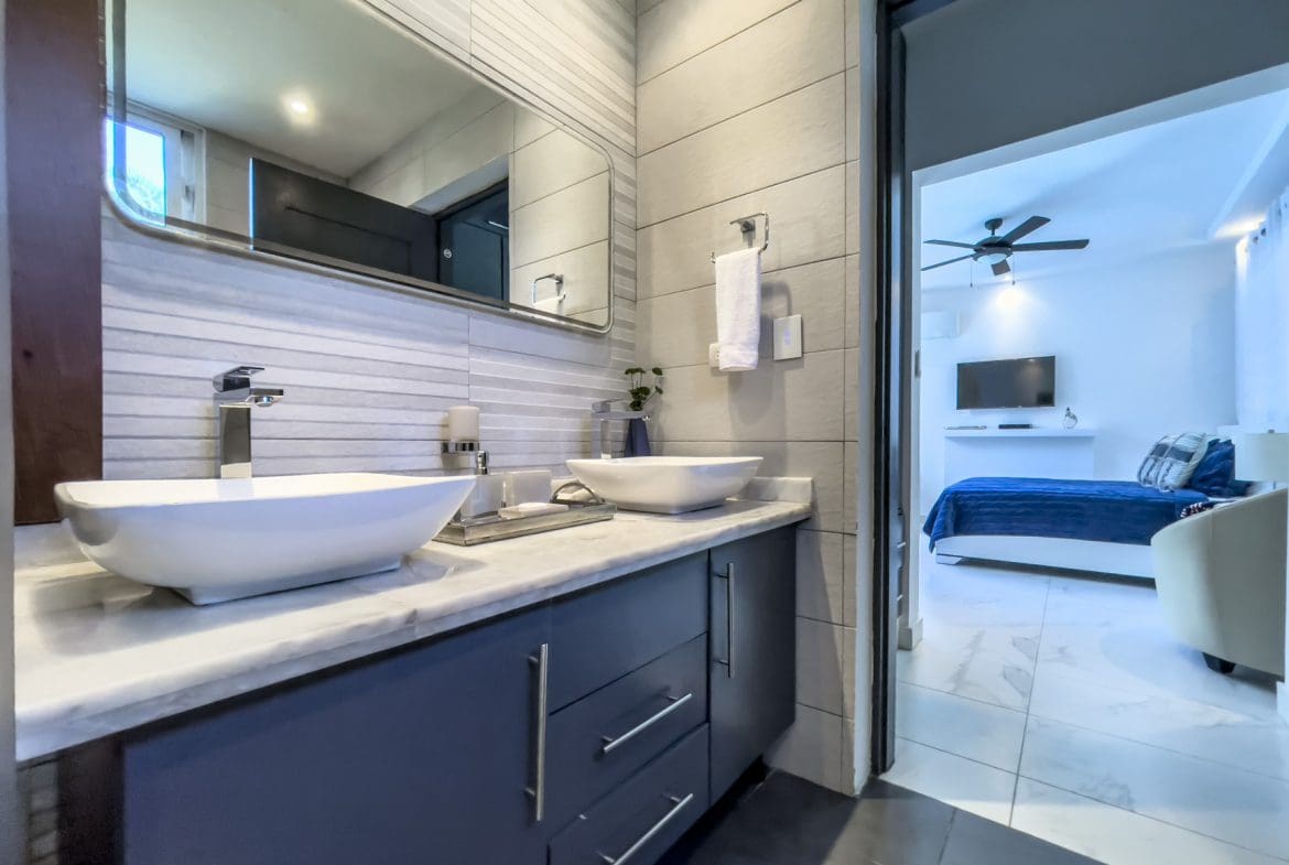 buyDRproperty Modern bathroom with dual sinks and a view into a Sosúa Ocean Village 3-bedroom villa. Sosua Real Estate