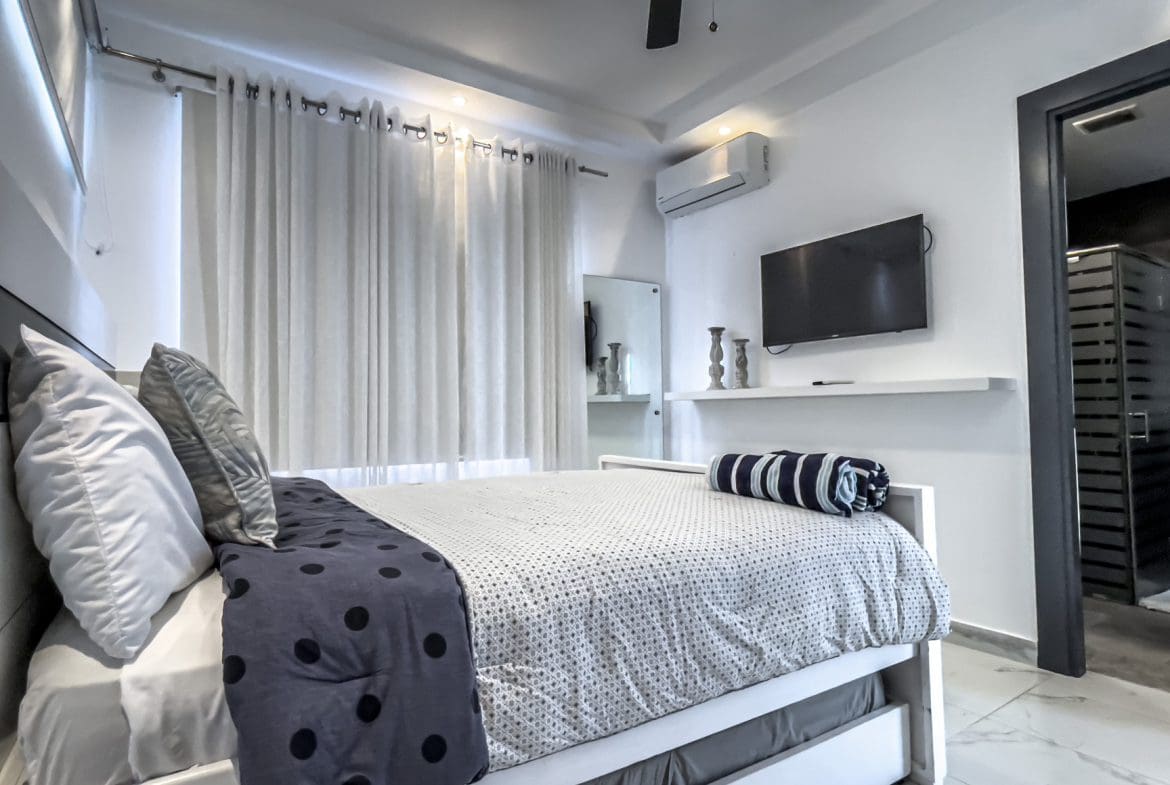 buyDRproperty Modern 3-bedroom villa bedroom in Sosúa Ocean Village with bed and TV. Sosua Real Estate