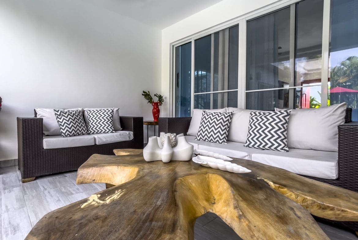 buyDRproperty Modern Sosúa Ocean Village villa living room with wooden coffee table and gray sofas. Sosua Real Estate