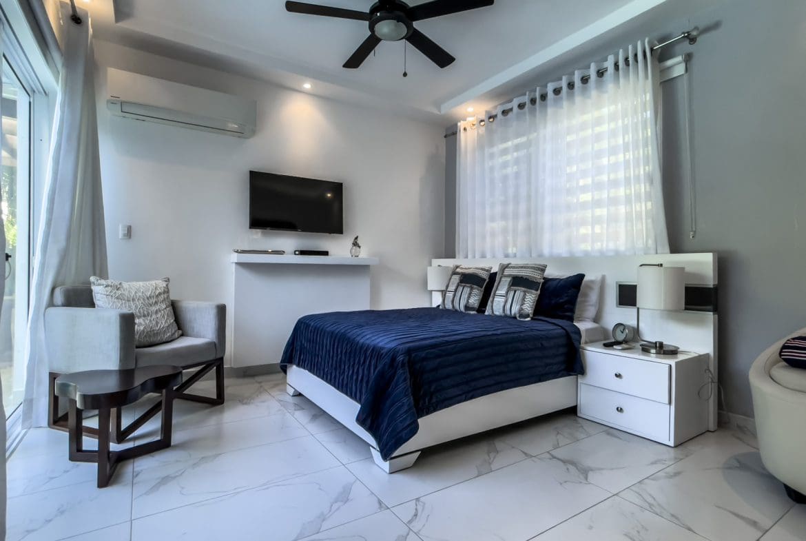 buyDRproperty Modern 3-bedroom villa bedroom interior in Sosúa Ocean Village with a blue comforter and marble floors. Sosua Real Estate