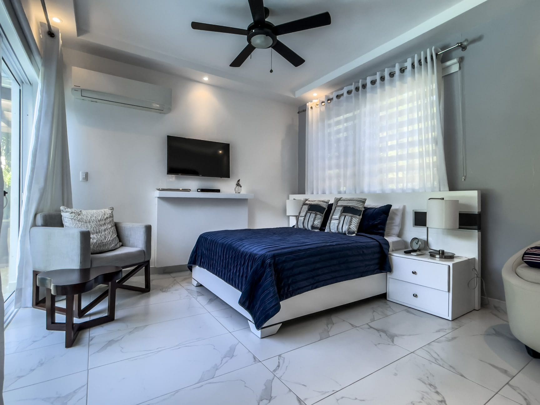 buyDRproperty Modern 3-bedroom villa bedroom interior in Sosúa Ocean Village with a blue comforter and marble floors. Sosua Real Estate