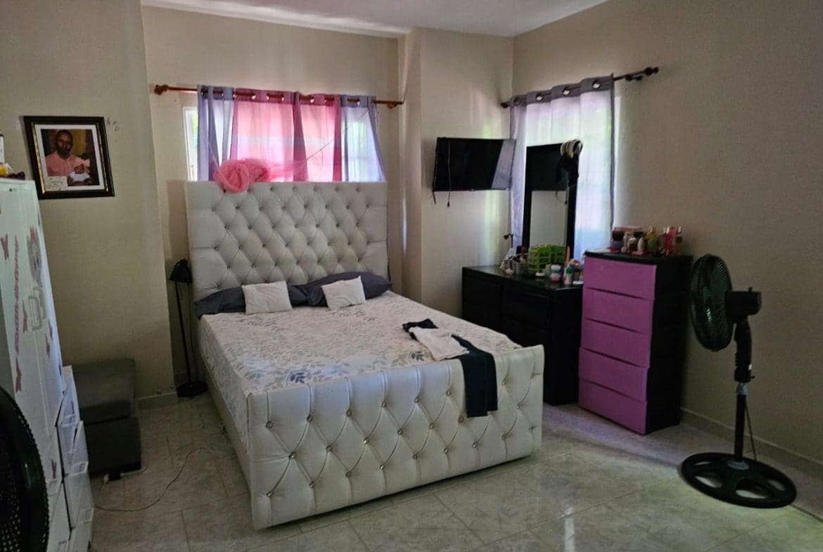 buyDRproperty Bedroom in a charming house for sale in Cabarete, featuring a tufted headboard bed. Sosua Real Estate
