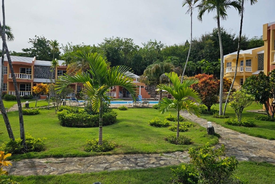 buyDRproperty Lush green courtyard with palm trees and a pool, near a Great Condo for Sale. Sosua Real Estate