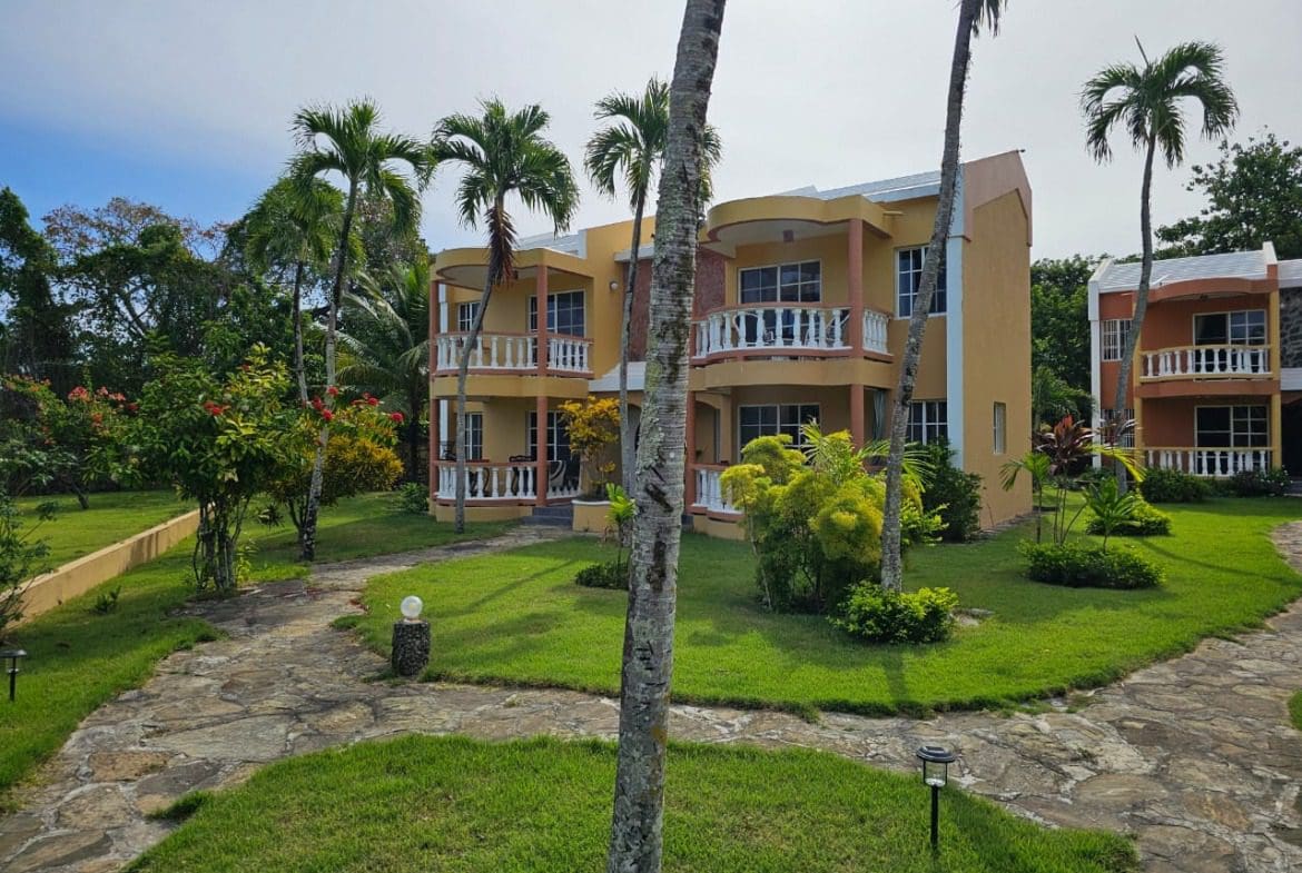 buyDRproperty Exterior view of a Great Condo for Sale near SOSUA Center, with palm trees and stone pathway. Sosua Real Estate