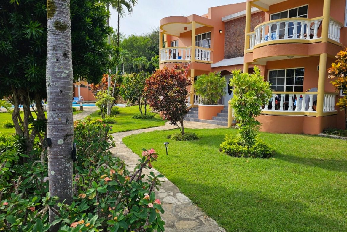 buyDRproperty Townhouse for sale close to SOSUA center with green lawns and a stone pathway. Sosua Real Estate