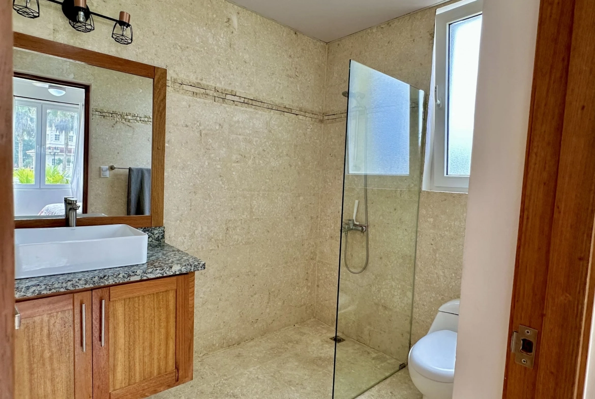 buyDRproperty Bathroom in a 2-bedroom condo for sale with a modern design, glass shower, and stylish vanity. Sosua Real Estate