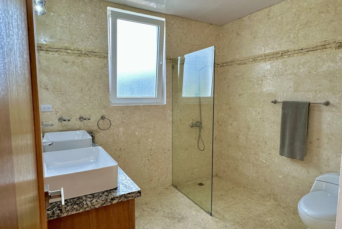 buyDRproperty Modern bathroom with glass shower, sink, and toilet. A 2-bedroom condo. Sosua Real Estate
