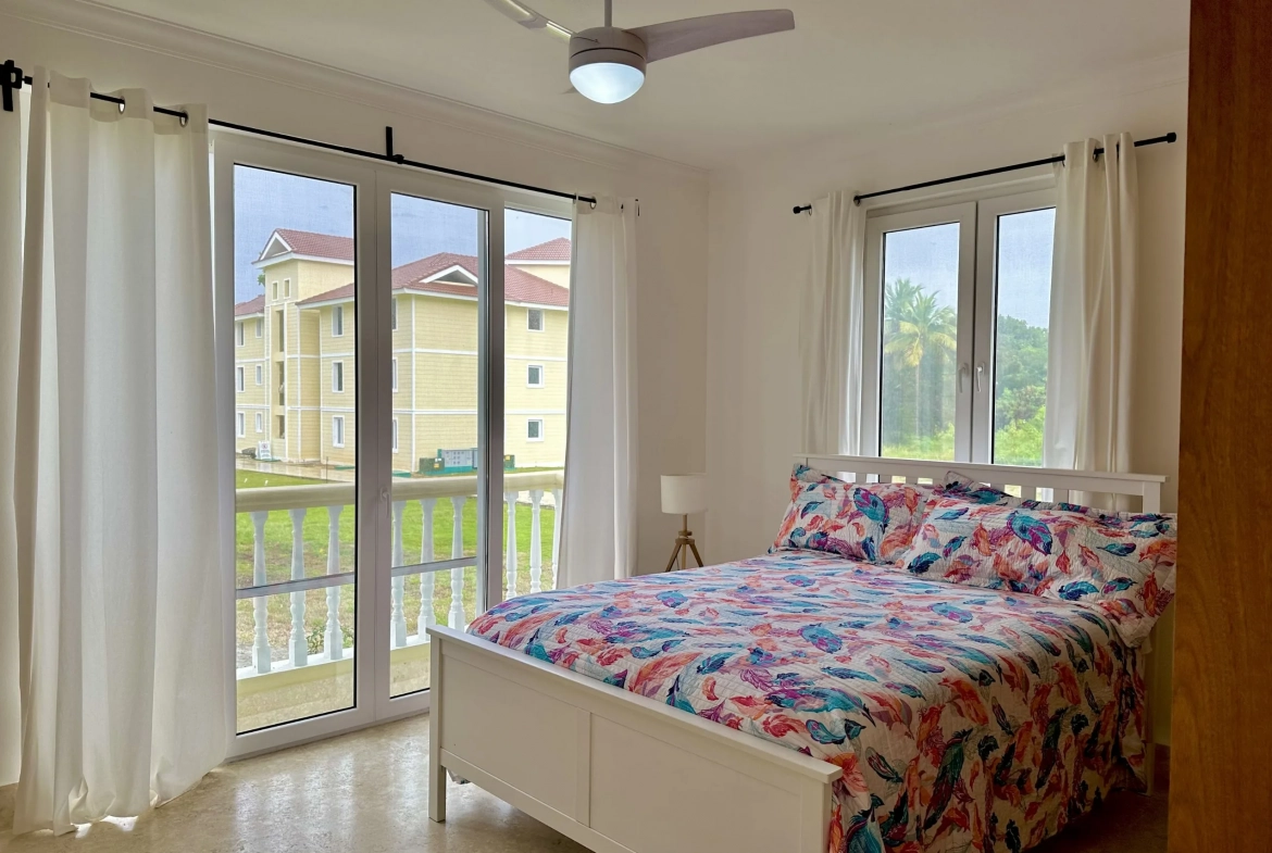 buyDRproperty Bright 2-bedroom condo bedroom with colorful bedding and large windows overlooking the property. Sosua Real Estate