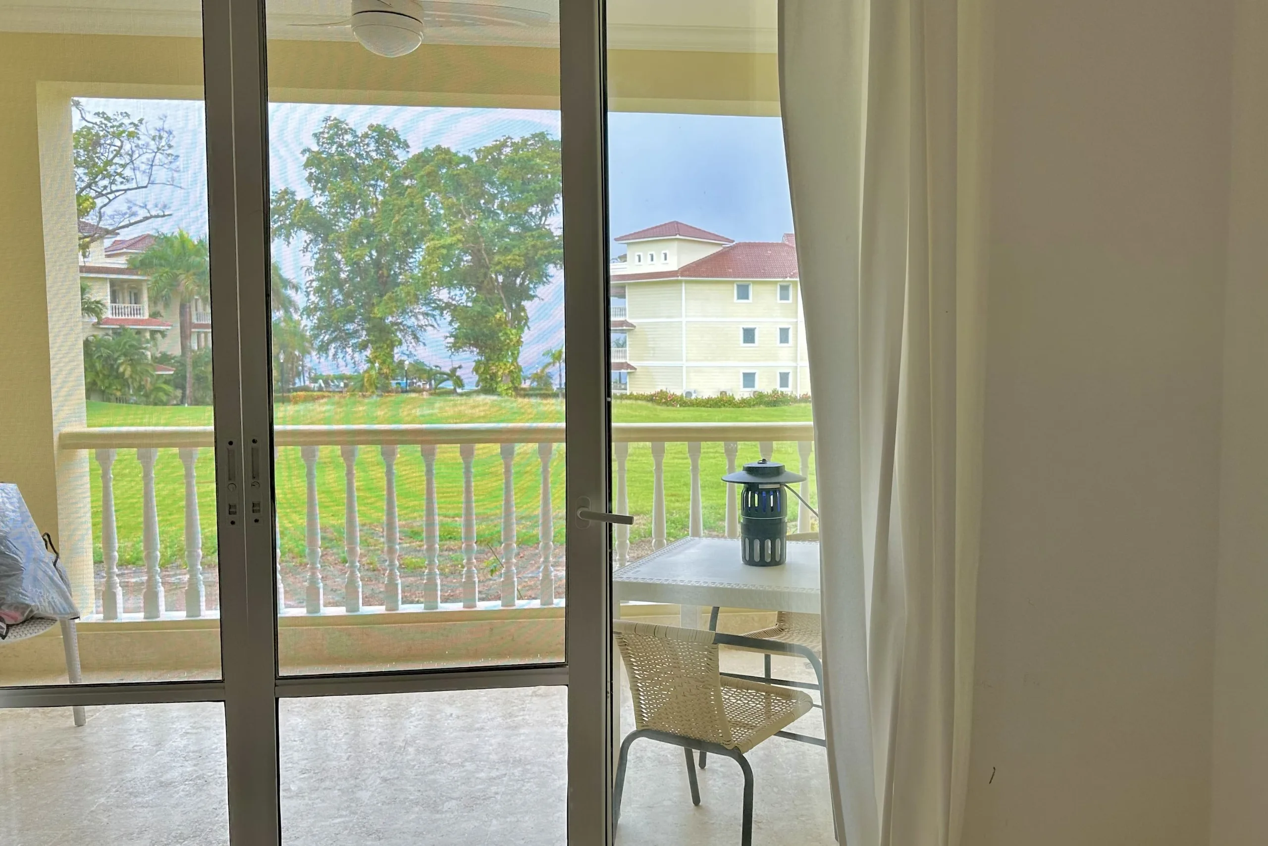 buyDRproperty View from a 2-bedroom condo balcony overlooking a green lawn and neighboring buildings. Sosua Real Estate