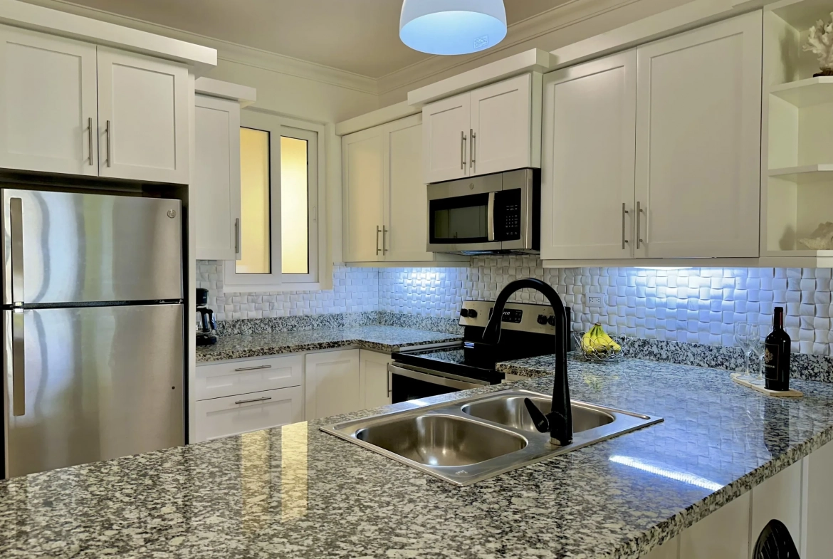 buyDRproperty Modern kitchen with white cabinets, stainless steel appliances, and granite countertops in a 2-Bedroom Condo. Sosua Real Estate
