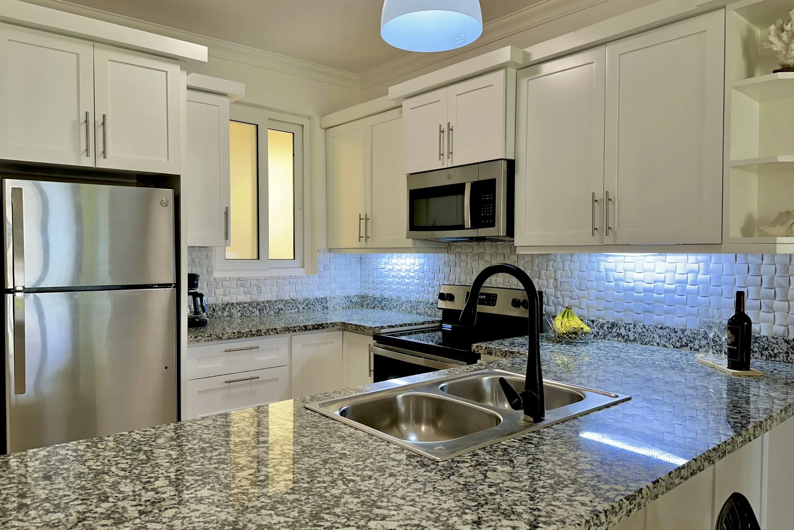 buyDRproperty Modern kitchen with white cabinets, stainless steel appliances, and granite countertops in a 2-Bedroom Condo. Sosua Real Estate