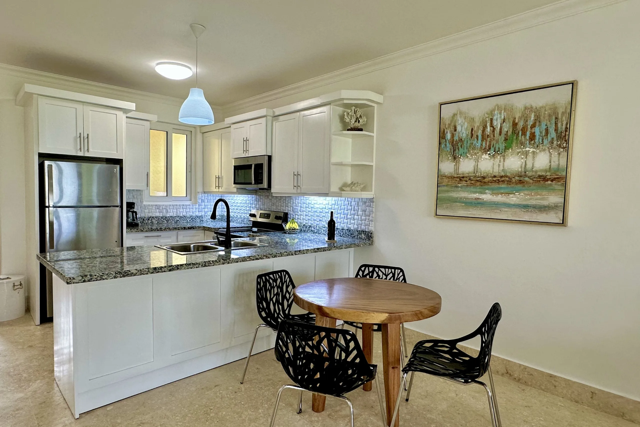 buyDRproperty Modern kitchen and dining area in a 2-Bedroom Condo with granite countertops and black chairs. Sosua Real Estate