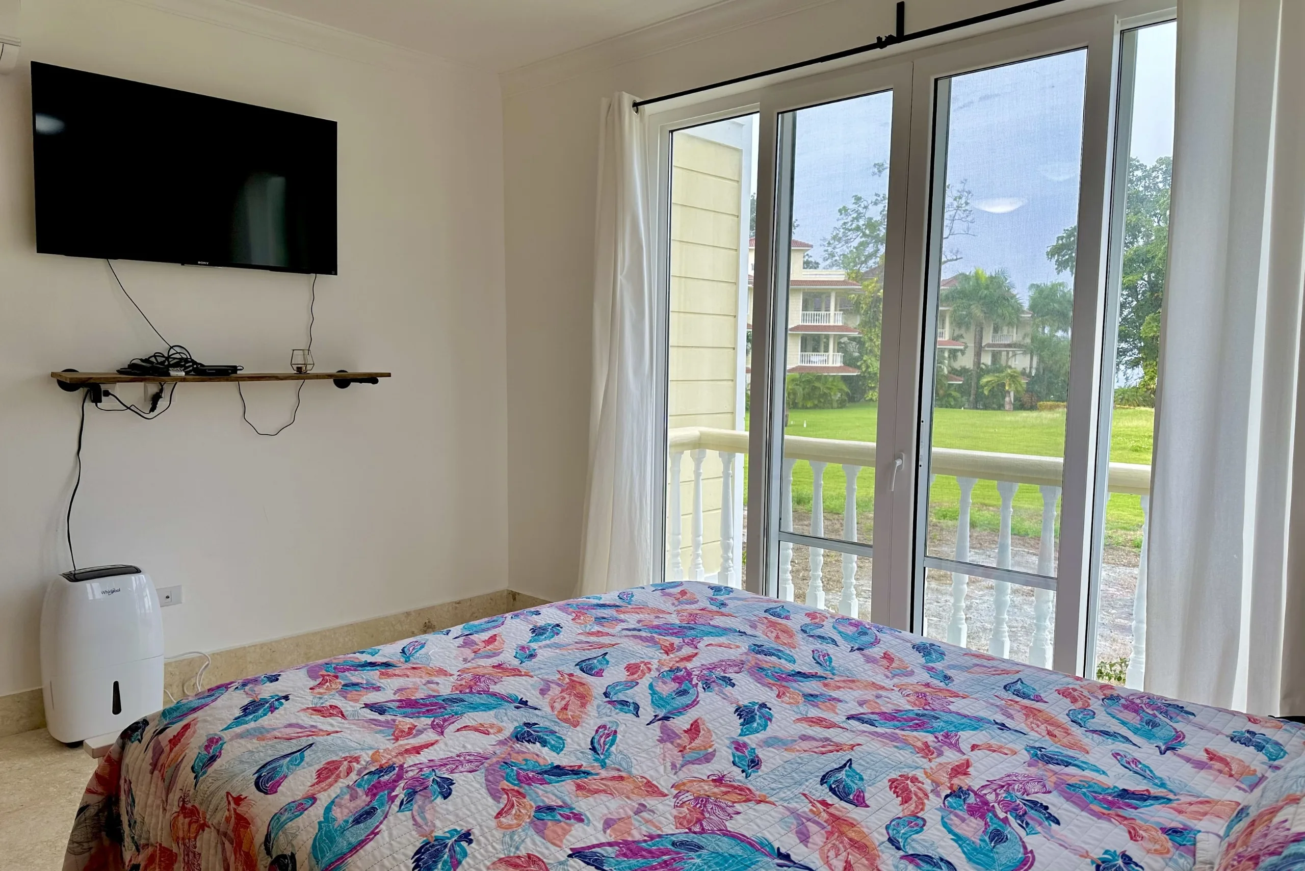 buyDRproperty Bedroom with a colorful bedspread, TV, and a view from the 2-bedroom condo. Sosua Real Estate
