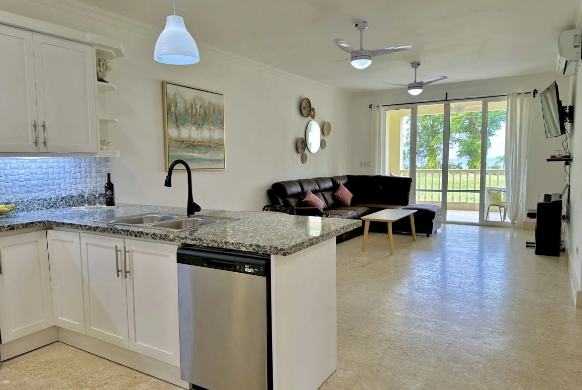 buyDRproperty Modern 2-Bedroom Condo interior with kitchen, living area, and balcony view Sosua Real Estate