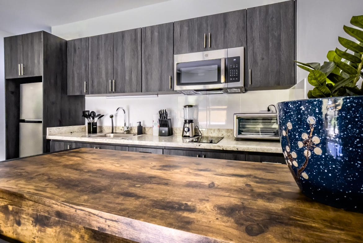 buyDRproperty Modern kitchen with dark wood cabinets and a wooden countertop in a one-bedroom condo. Sosua Real Estate