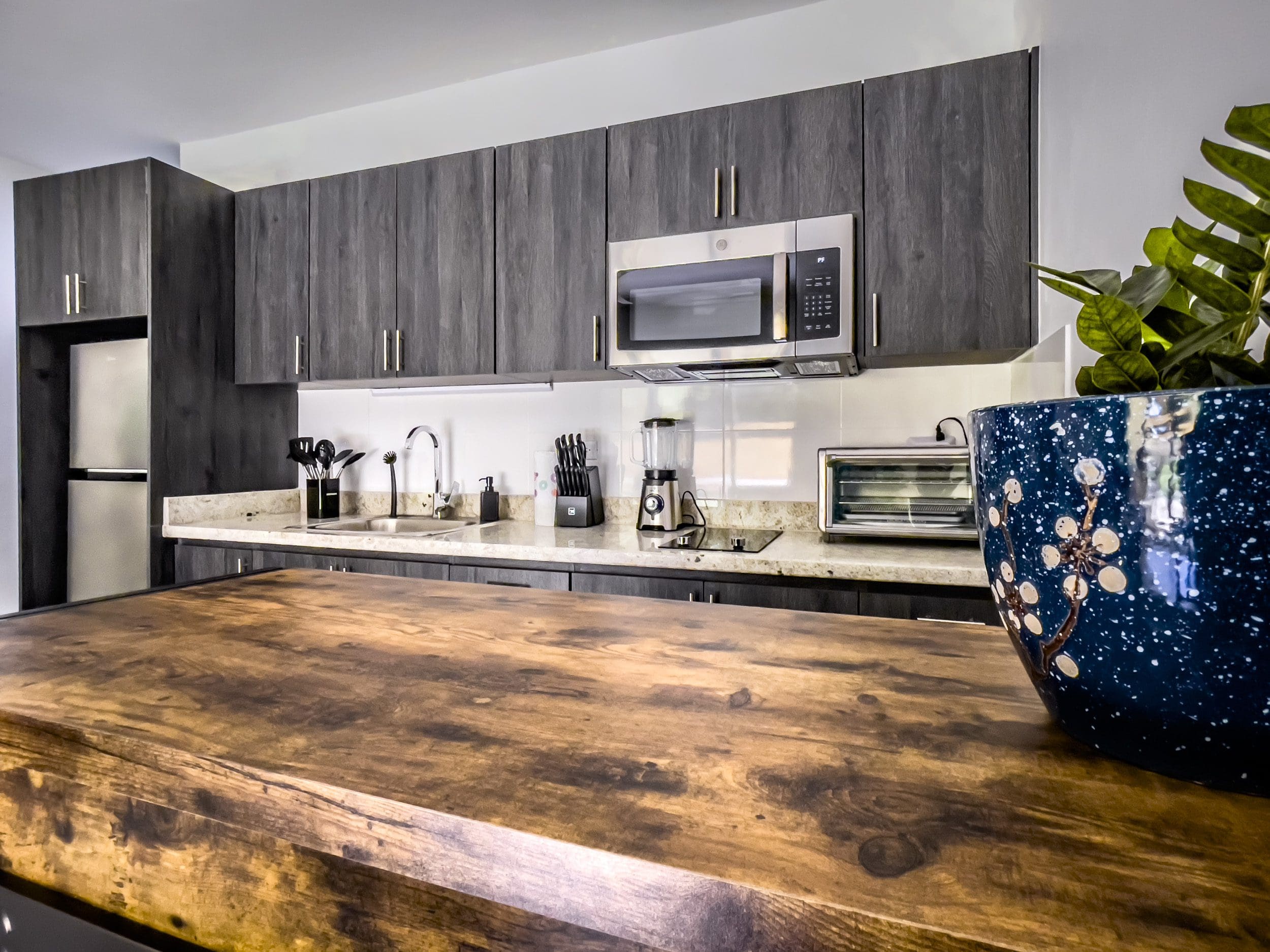 buyDRproperty Modern kitchen with dark wood cabinets and a wooden countertop in a one-bedroom condo. Sosua Real Estate