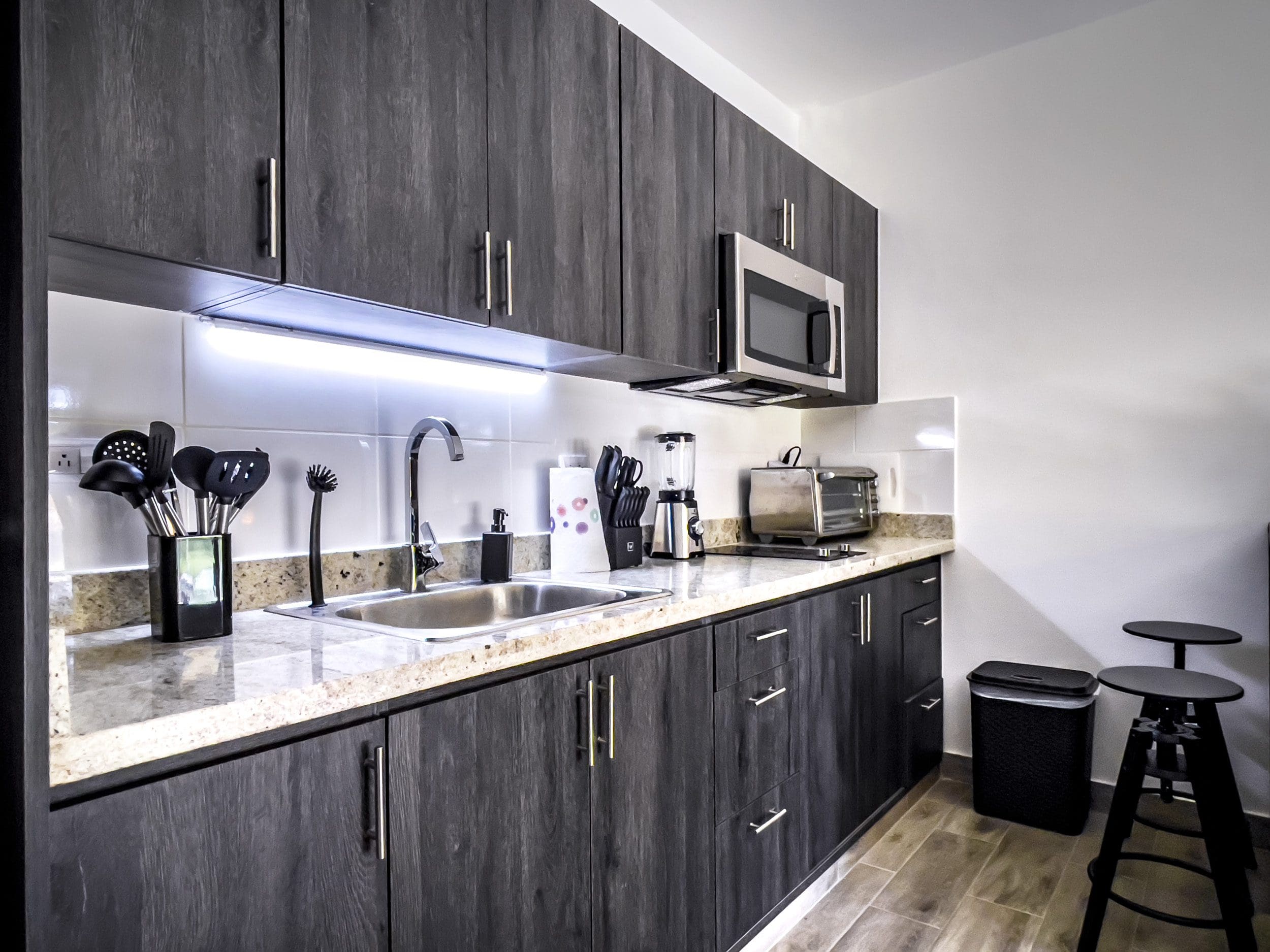 buyDRproperty Modern kitchen in a one-bedroom condo for sale in Sosua, featuring dark wood cabinets and stainless steel appliances. Sosua Real Estate