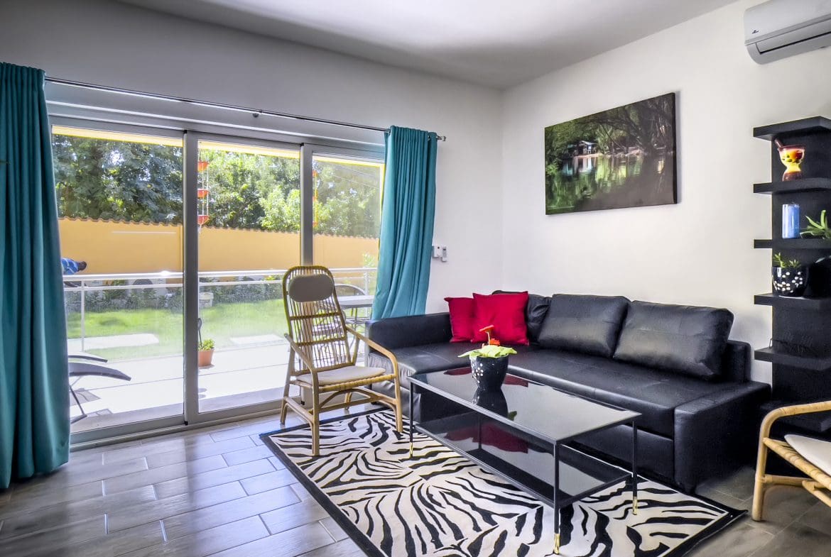 buyDRproperty Living room of a one bedroom condo with a black leather couch and zebra rug. Sosua Real Estate