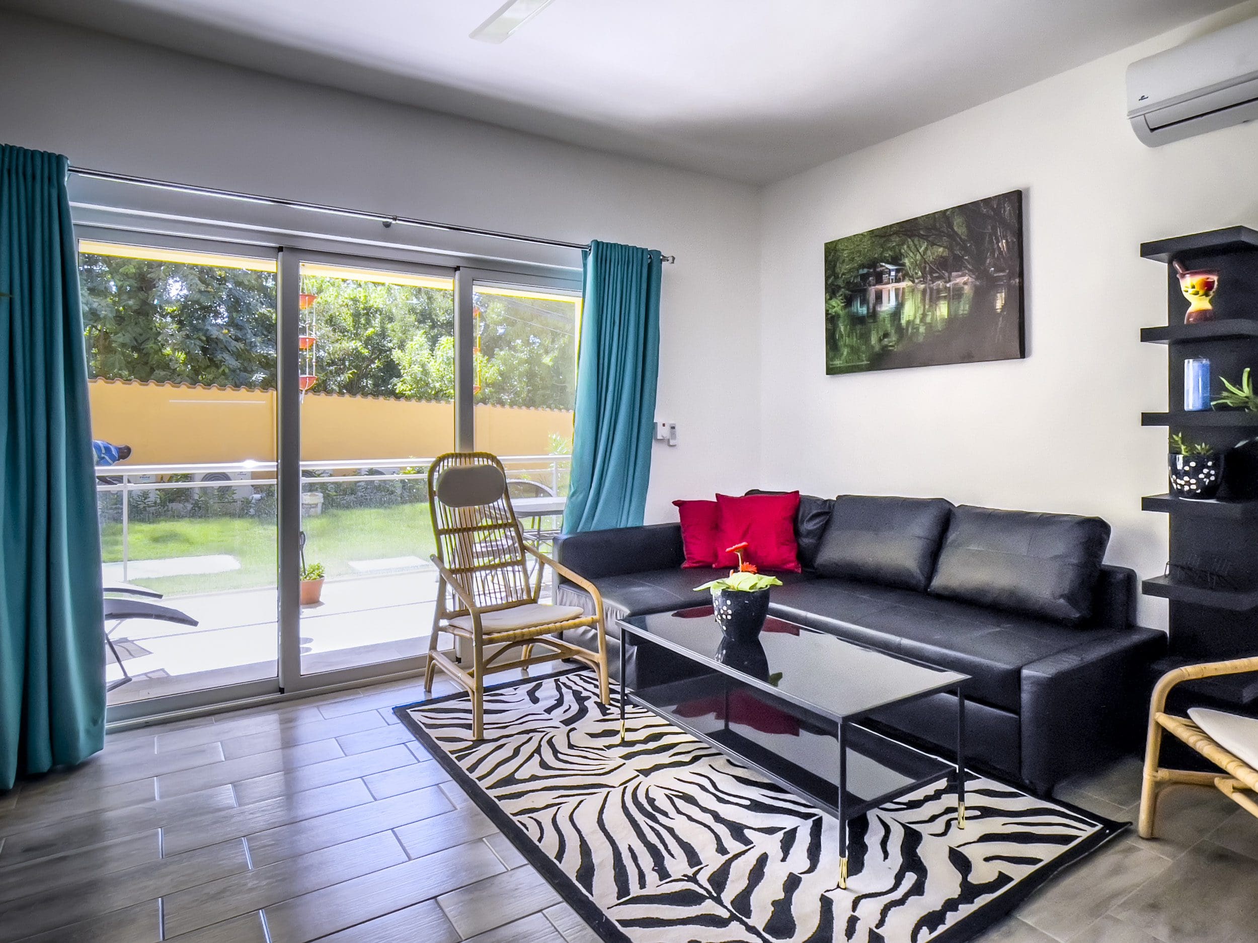 buyDRproperty Living room of a one bedroom condo with a black leather couch and zebra rug. Sosua Real Estate