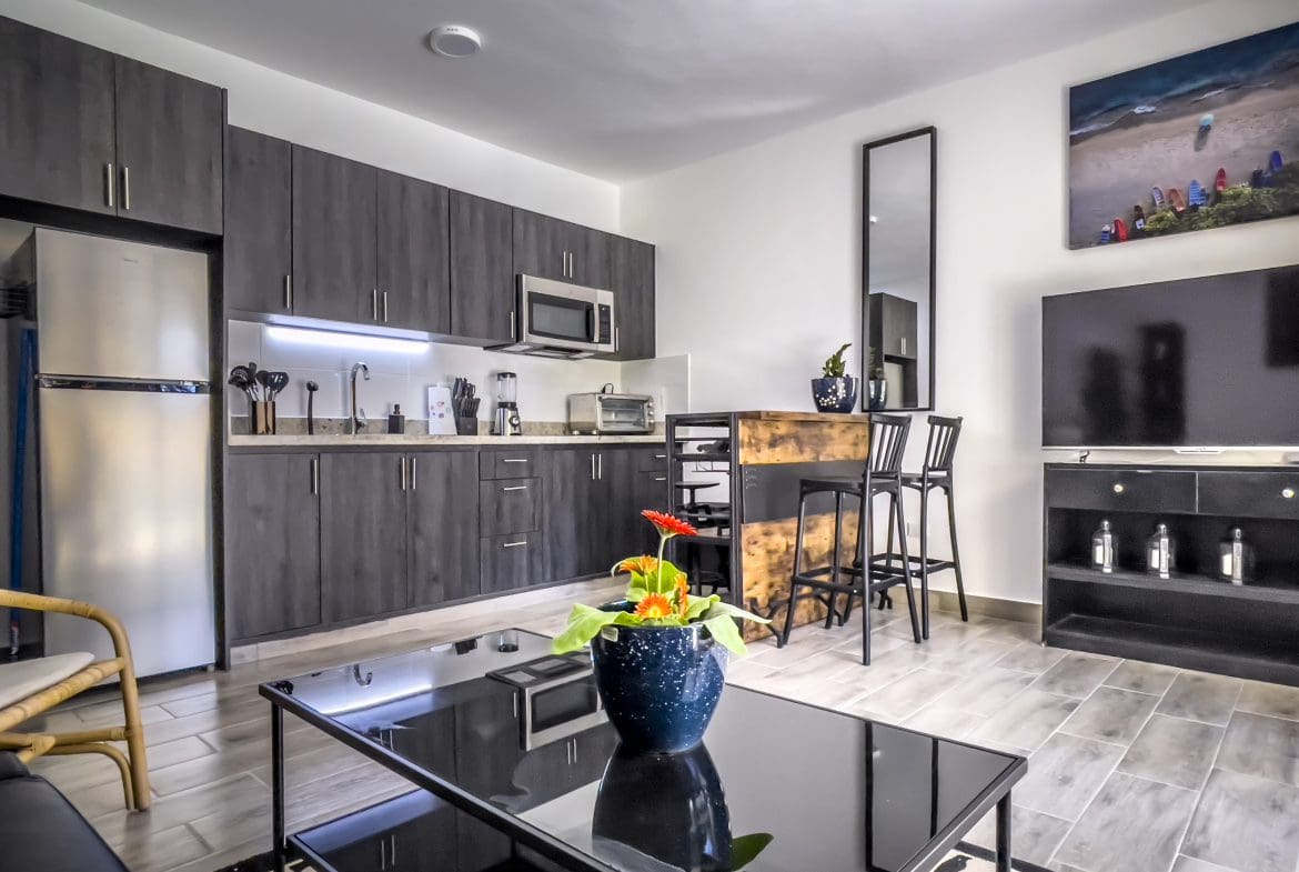 buyDRproperty Modern one bedroom condo kitchen with dark cabinets and bar Sosua Real Estate