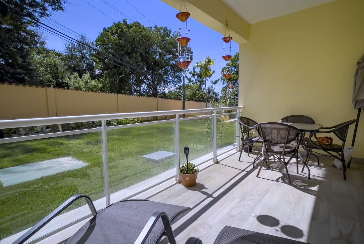 buyDRproperty Balcony of a one-bedroom condo for sale in Sosua with outdoor furniture, view of the yard, and hanging decor. Sosua Real Estate