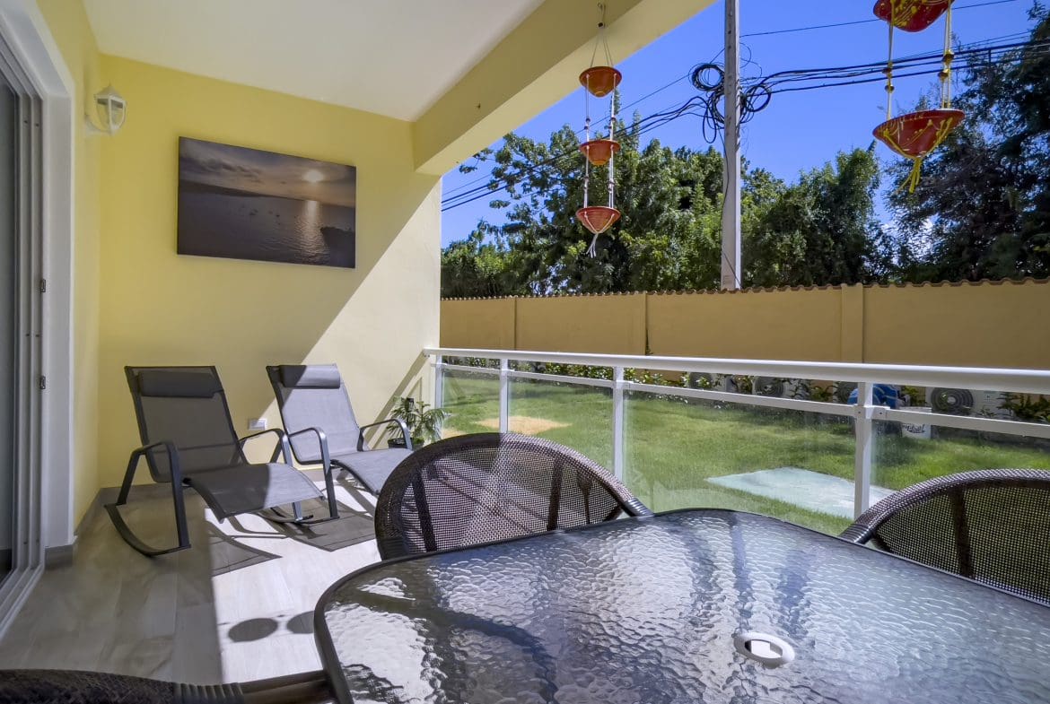 buyDRproperty Patio of a one bedroom condo in Sosua with glass table and chairs. Sosua Real Estate