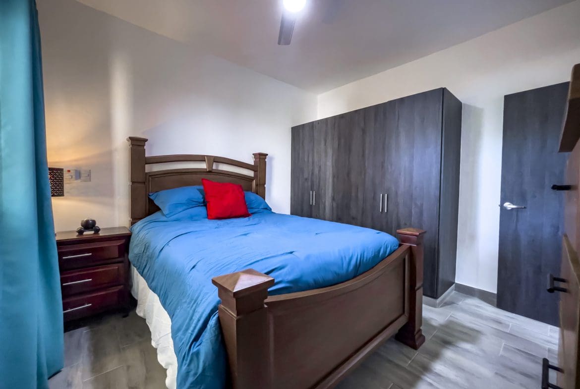 buyDRproperty One bedroom condo bedroom with blue bedding and red pillow Sosua Real Estate