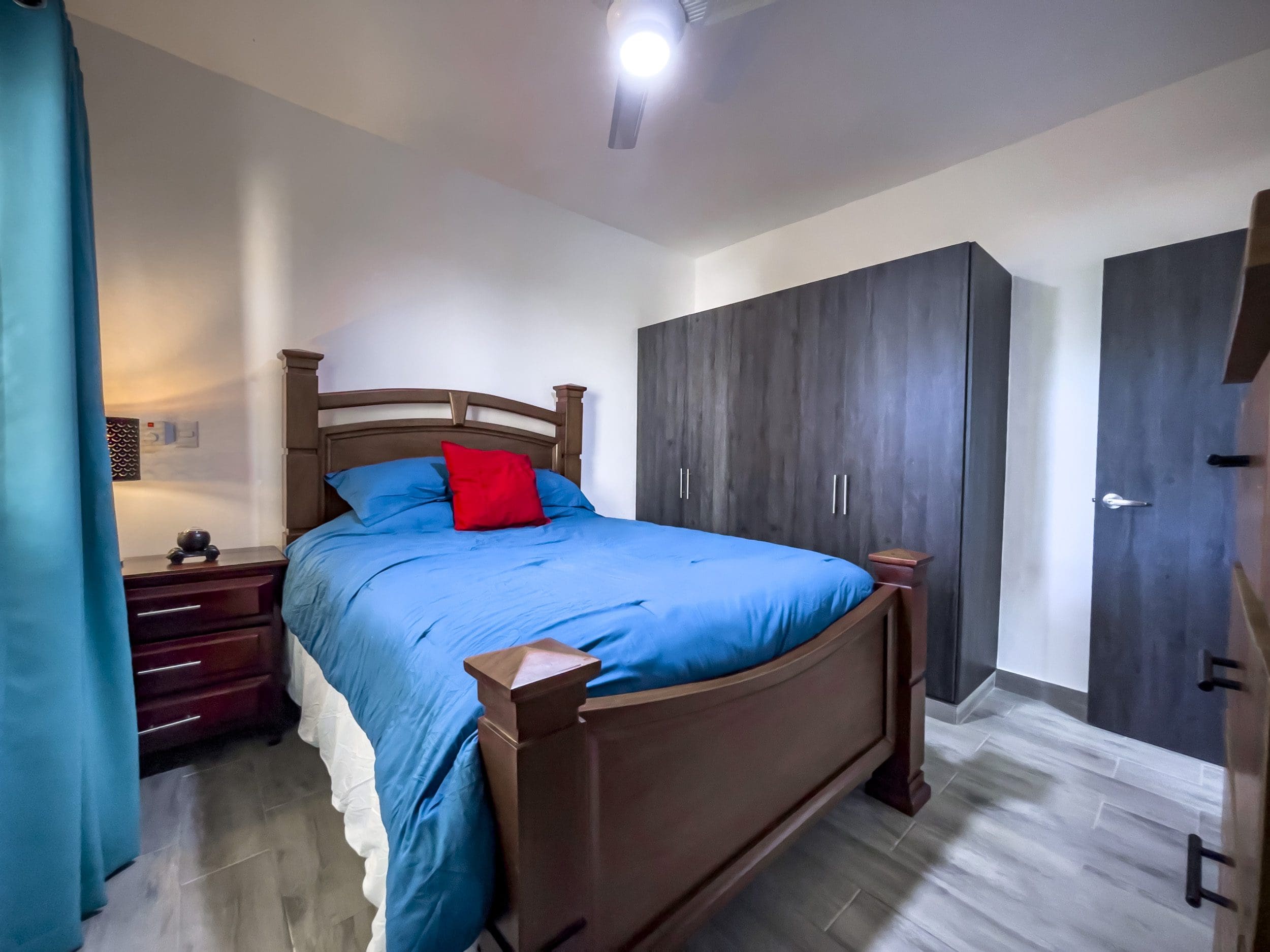 buyDRproperty One bedroom condo bedroom with blue bedding and red pillow Sosua Real Estate
